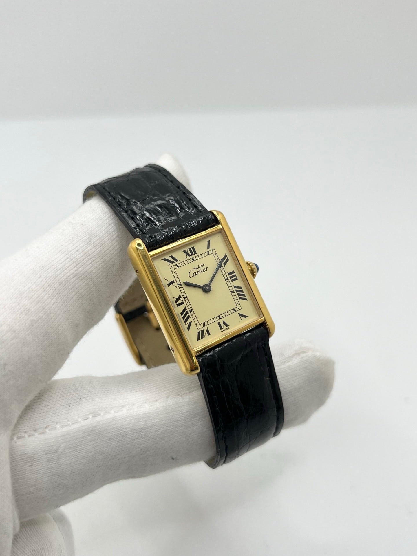 Montre Cartier Tank Vermeil mécanique vintage en argent plaqué or, dotée d’un mouvement à remontage manuel. Ce modèle emblématique présente un cadran champagne à chiffres romains, un boîtier rectangulaire de 23 x 30 mm et un bracelet en cuir de crocodile noir avec boucle ardillon en acier. Élégante et intemporelle, cette montre Cartier Must Tank d’occasion en très bon état séduit les amateurs d’horlogerie classique et de montres de luxe vintage.
