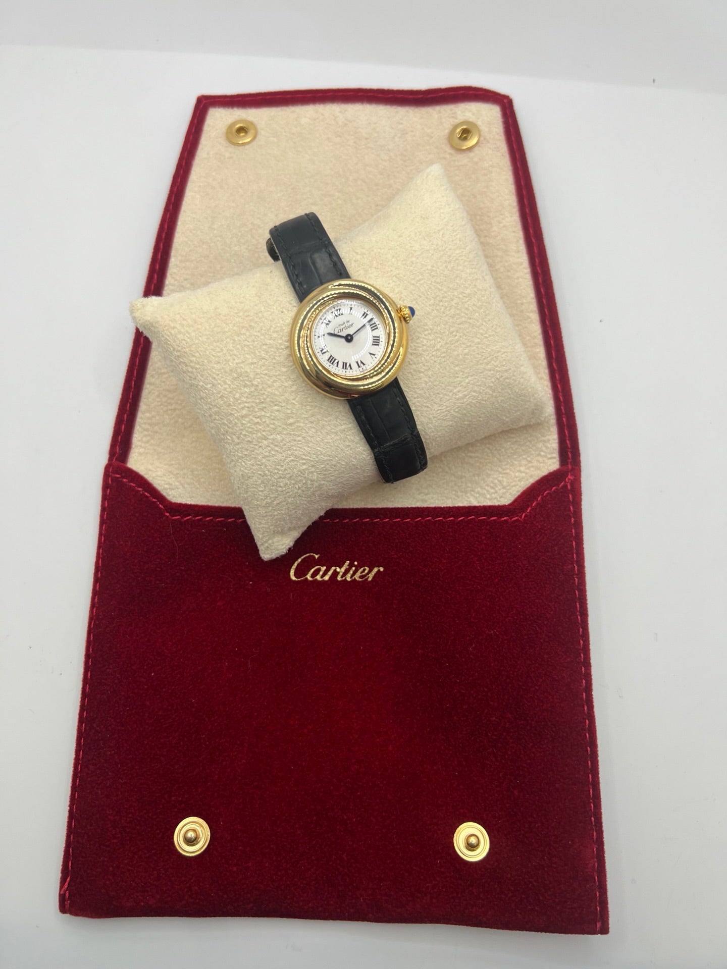 Montre Cartier Trinity référence 2735 pour femme en argent avec boîtier de 27 mm, cadran blanc à chiffres romains et verre saphir. Cette montre Cartier Trinity à mouvement quartz est équipée d’un bracelet en cuir avec boucle déployante en acier. Son design intemporel et élégant en fait une montre de luxe vintage idéale pour les collectionneuses ou pour un usage quotidien. Modèle d’occasion en très bon état, avec de légères traces d’usure, livré avec son coffret d’origine.