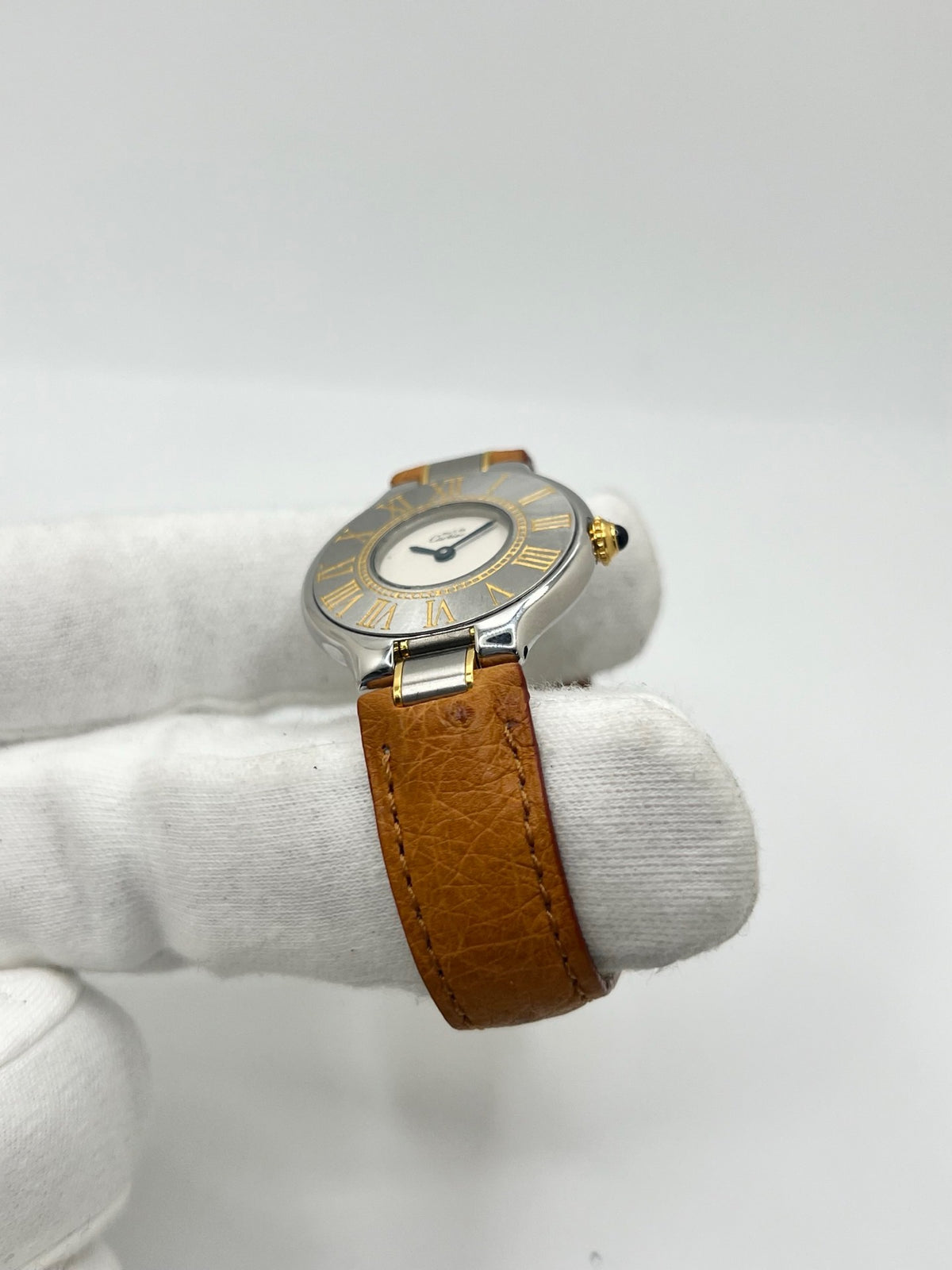 Montre Cartier 21 Must de Cartier 9011 pour femme, équipée d’un mouvement quartz et d’un boîtier en acier de 28 mm. Son cadran blanc offre une esthétique élégante et intemporelle. Cette montre Cartier est montée sur un bracelet brun en cuir avec boucle déployante à plis. En bon état, elle présente des traces d’usure visibles et perceptibles, notamment quelques rayures, éraflures et petites bosses. Révisée en interne en septembre 2026.
