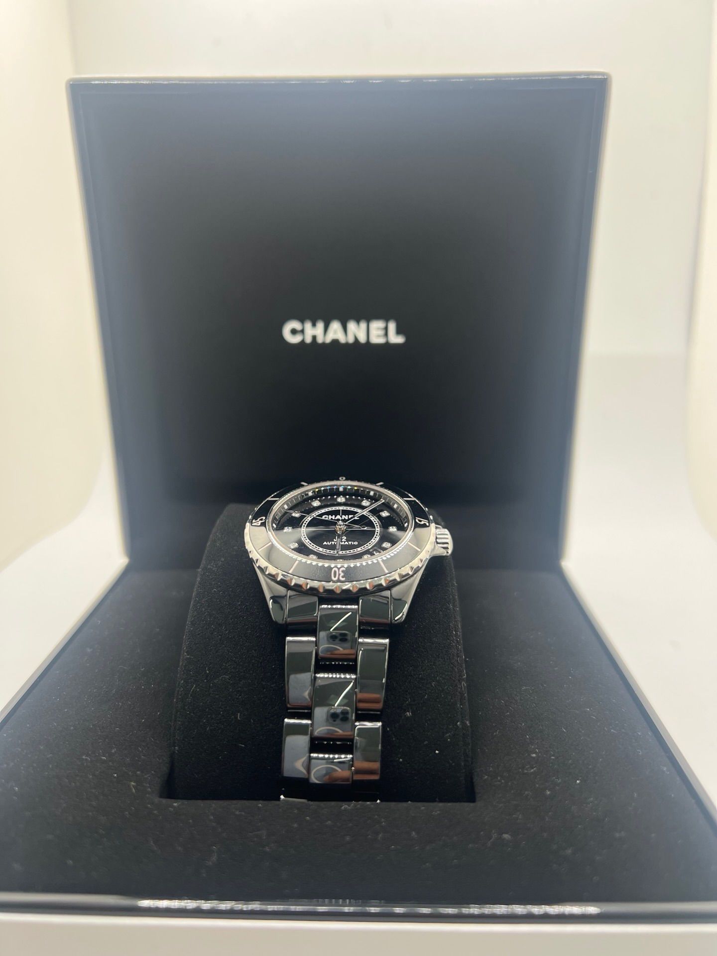 Montre Chanel J12 12.1 en céramique noire avec sertissage de diamants, alliant élégance et performance. Mouvement automatique de précision, boîtier de 38 mm et verre saphir. Modèle de luxe d'occasion en excellent état, livré avec coffret d'origine. Idéal pour collectionneurs et amateurs de haute horlogerie.