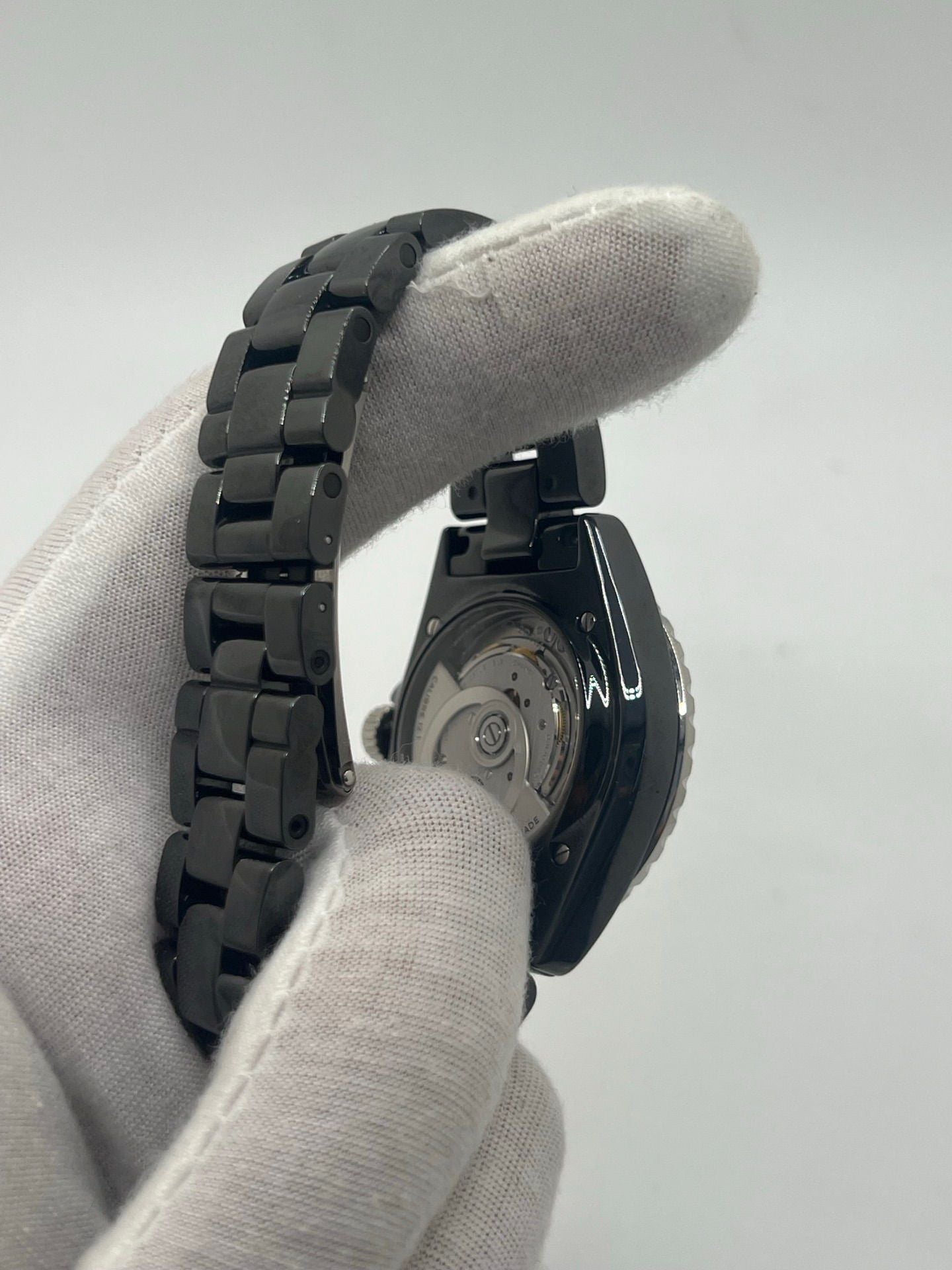 Montre Chanel J12 12.1 en céramique noire avec sertissage de diamants, alliant élégance et performance. Mouvement automatique de précision, boîtier de 38 mm et verre saphir. Modèle de luxe d'occasion en excellent état, livré avec coffret d'origine. Idéal pour collectionneurs et amateurs de haute horlogerie.