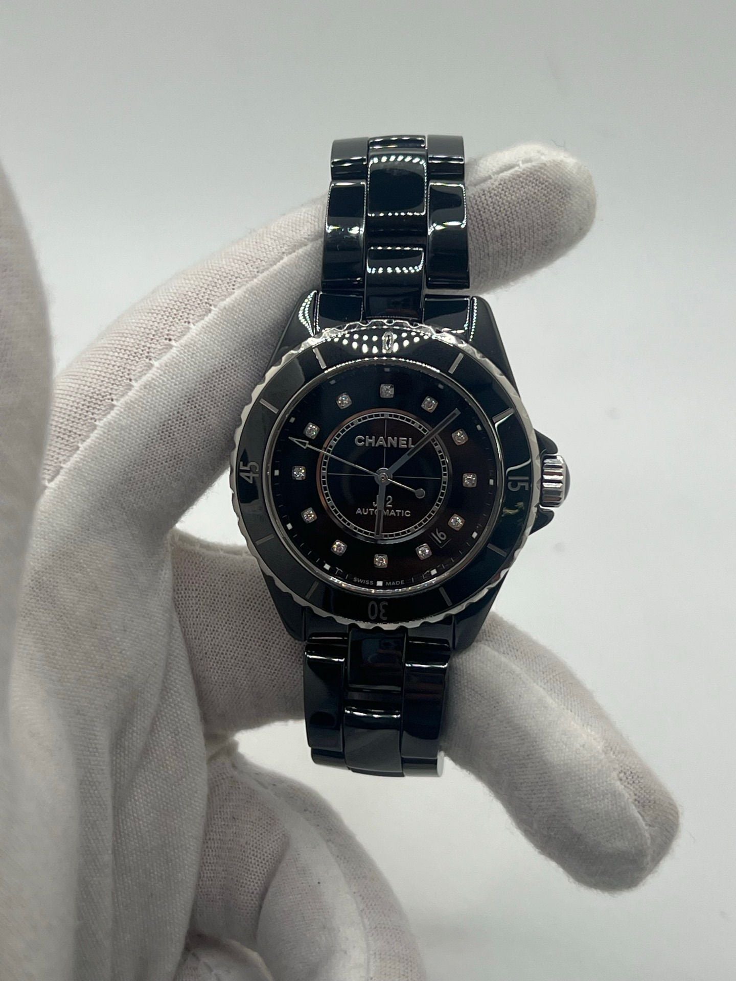 Montre Chanel J12 12.1 en céramique noire avec sertissage de diamants, alliant élégance et performance. Mouvement automatique de précision, boîtier de 38 mm et verre saphir. Modèle de luxe d'occasion en excellent état, livré avec coffret d'origine. Idéal pour collectionneurs et amateurs de haute horlogerie.