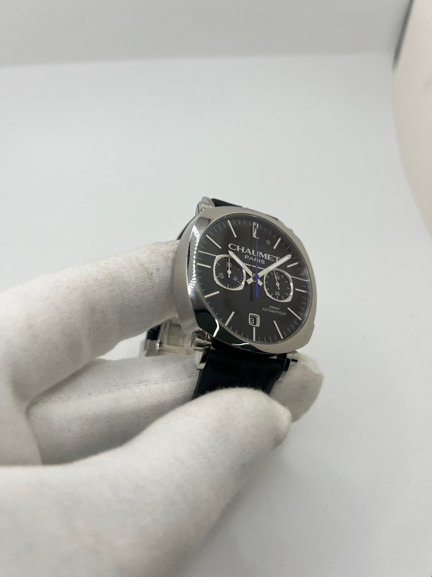 Montre Chaumet Dandy réf. 1229 pour homme ou unisexe, dotée d’un mouvement automatique. Boîtier en acier de 40 mm avec lunette assortie et verre saphir résistant aux rayures. Cadran noir à index bâtons, fonction chronographe et affichage de la date. Bracelet en cuir noir avec boucle déployante en acier. Montre de luxe d’occasion en très bon état, présentant de légères traces d’usure. Révisée en interne le 23 juin 2026, livrée avec coffret d’origine, sans papiers. Disponible à Paris. 