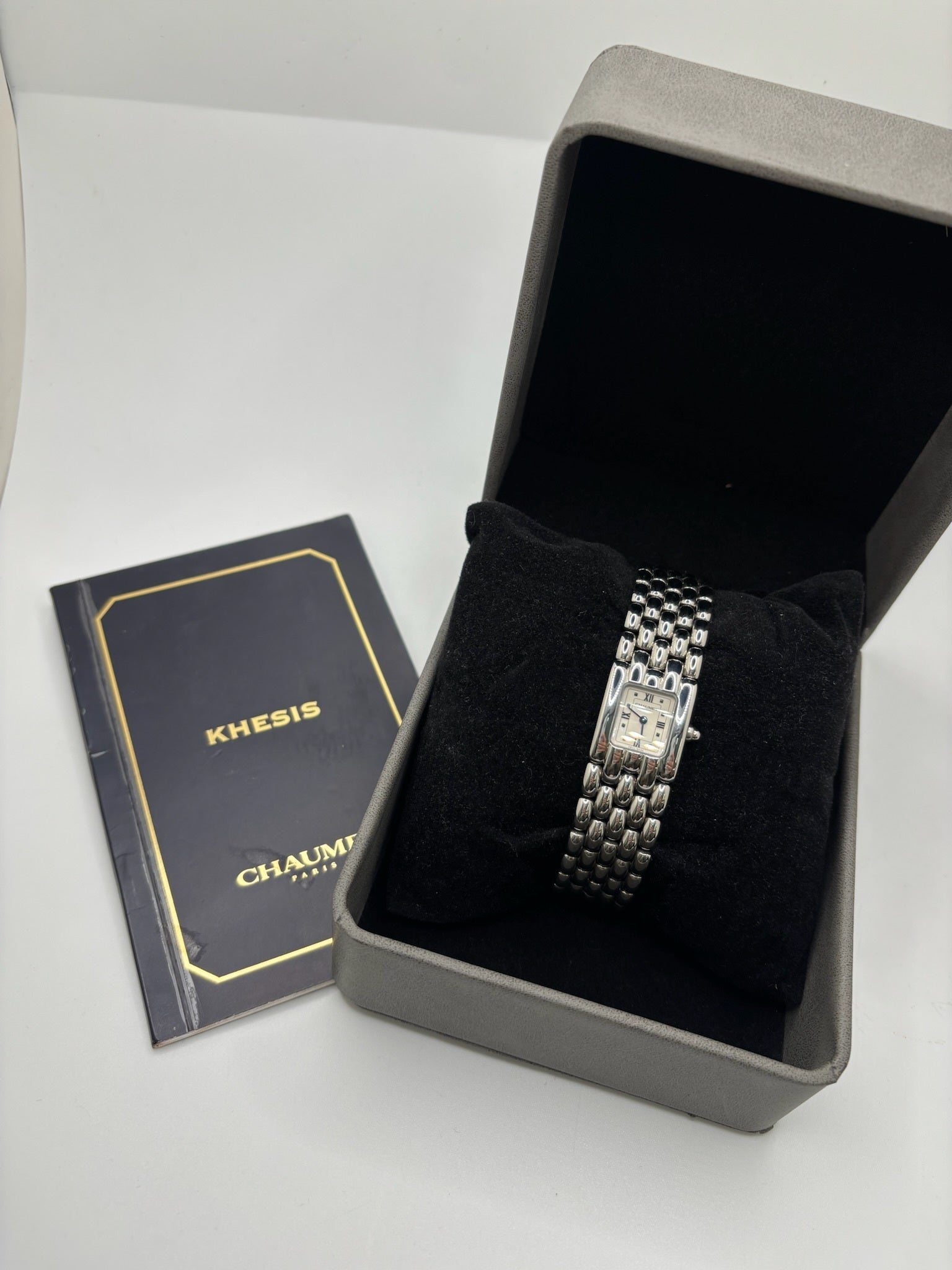 Montre Chaumet Khesis femme en acier avec mouvement quartz, cadran blanc à chiffres romains et verre saphir. Cette montre de luxe au design joaillier emblématique se distingue par son boîtier rectangulaire de 21 x 17 mm et son bracelet en acier intégré. Élégante et raffinée, cette Chaumet Khesis vintage de 1998 est accompagnée de ses papiers d’origine. Montre femme d’occasion en très bon état, idéale pour les collectionneuses et amatrices d’horlogerie de prestige.