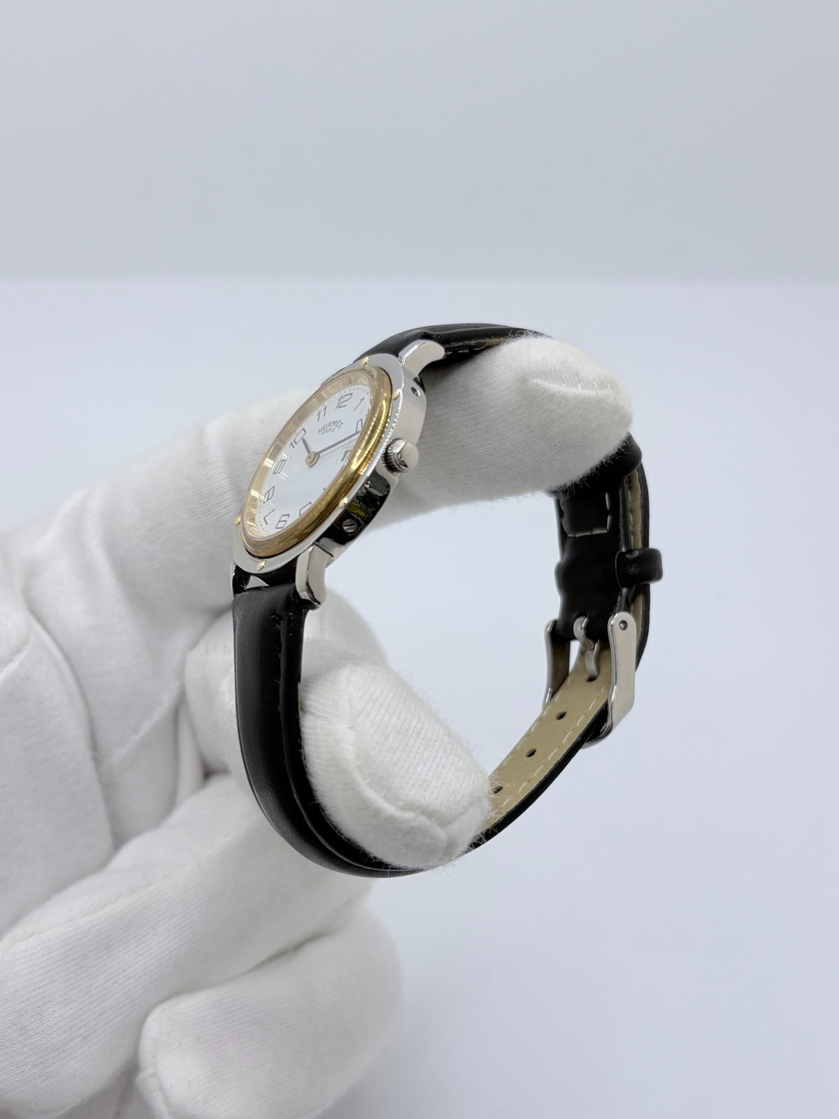Montre Hermès Clipper pour femme en acier, équipée d’un mouvement à quartz. Son boîtier de 30 mm est associé à une lunette en or jaune, un cadran blanc avec chiffres arabes et un verre saphir. Cette montre Hermès Clipper est montée sur un bracelet en cuir de vache noir avec boucle ardillon en acier. Un modèle élégant et intemporel de la collection Clipper, idéal pour les amateurs de montres de luxe.