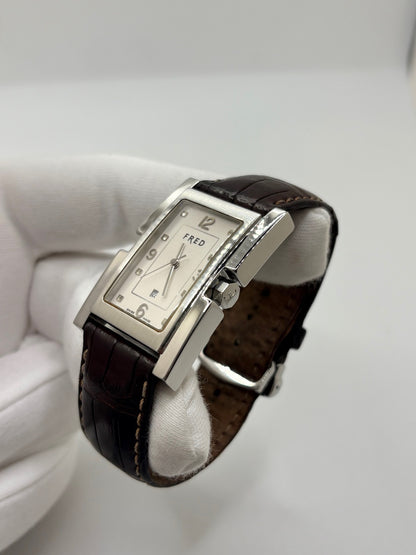Montre Fred Tank R09-100 en excellent état, dotée d’un mouvement quartz et d’un boîtier en acier de 33 × 27 mm. Cette montre élégante présente un cadran blanc avec chiffres arabes, protégé par un verre saphir. Elle est accompagnée d’un bracelet en cuir brun avec boucle en acier. Modèle homme ou unisexe, cette Fred Tank R09-100 séduit par son design classique et intemporel, idéal pour compléter une tenue élégante au quotidien.
