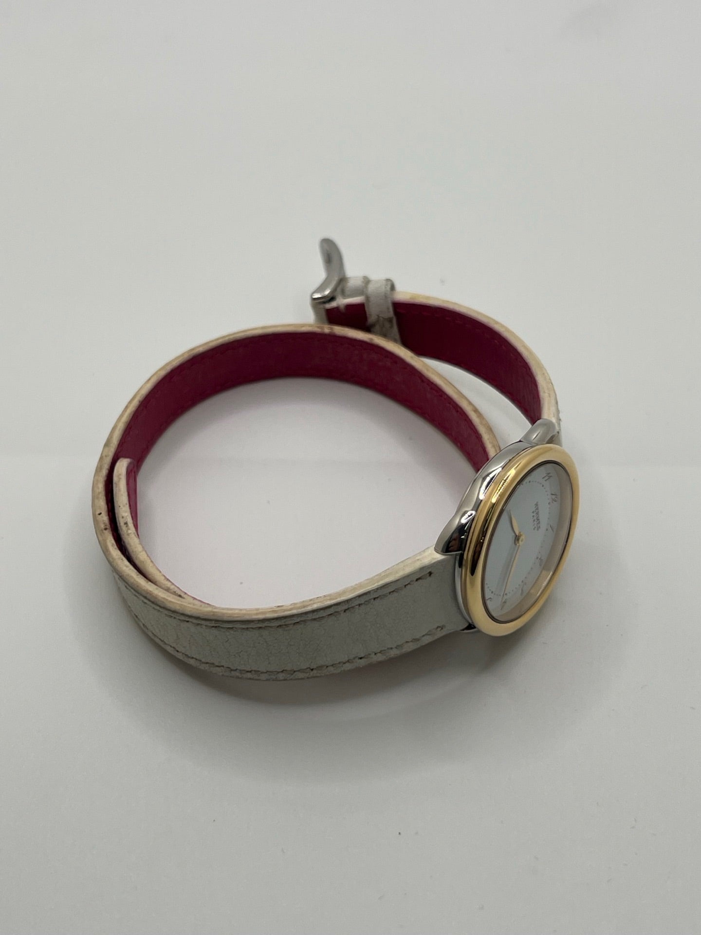 Élégante montre Hermès Arceau pour femme, boîtier en or et acier, cadran blanc aux chiffres arabes et bracelet en cuir beige. Ce garde-temps emblématique allie raffinement et savoir-faire horloger français, offrant un design intemporel et une précision quartz idéale pour un style classique et chic.