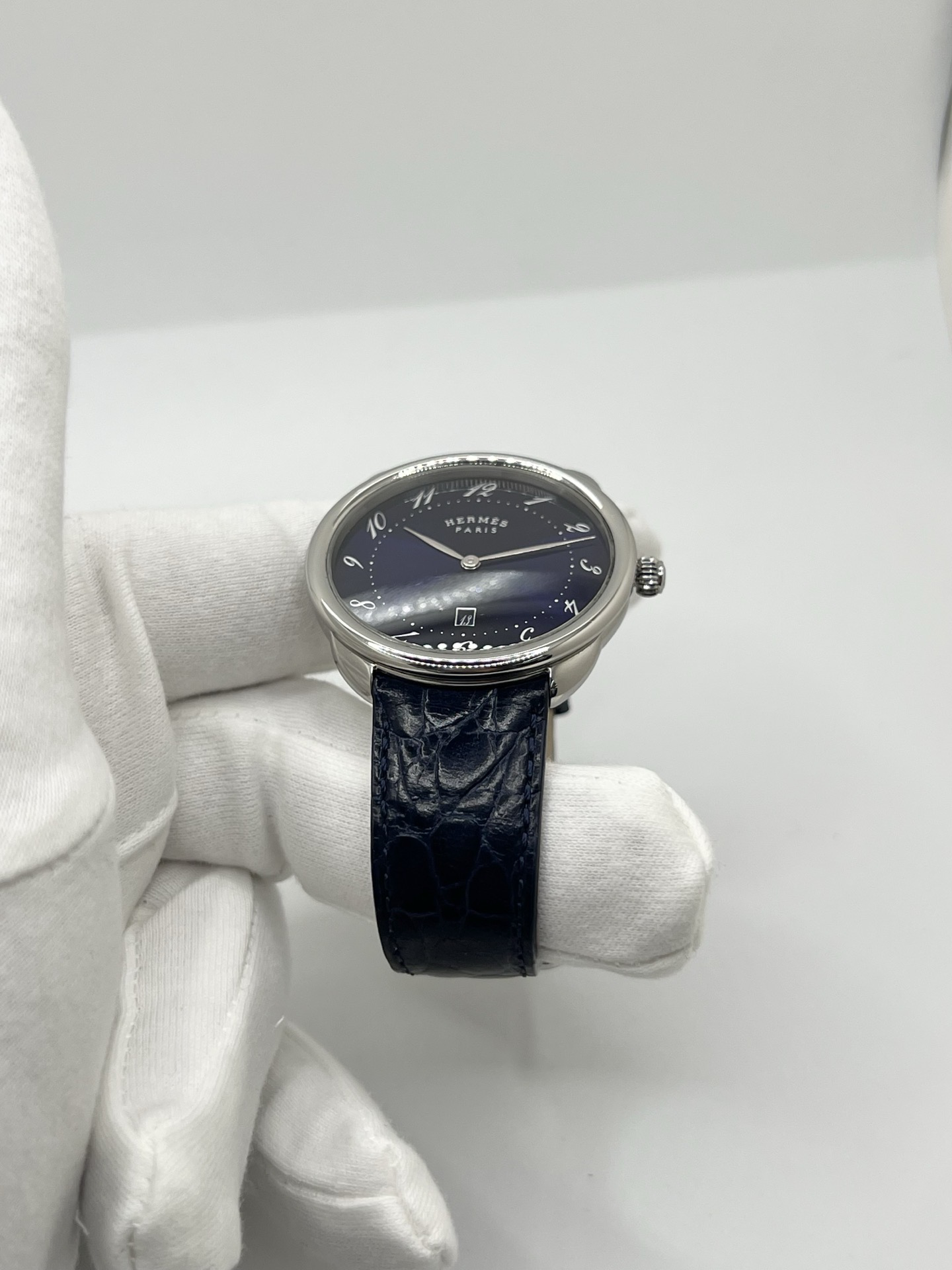 Montre Hermès Arceau grand modèle AR7Q.810 en acier avec cadran blanc épuré, chiffres arabes inclinés signature de la collection Arceau, mouvement quartz précis et bracelet en cuir élégant. Design intemporel et raffiné, idéal pour une tenue chic au quotidien ou une occasion spéciale, alliant savoir-faire horloger et esthétique minimaliste.