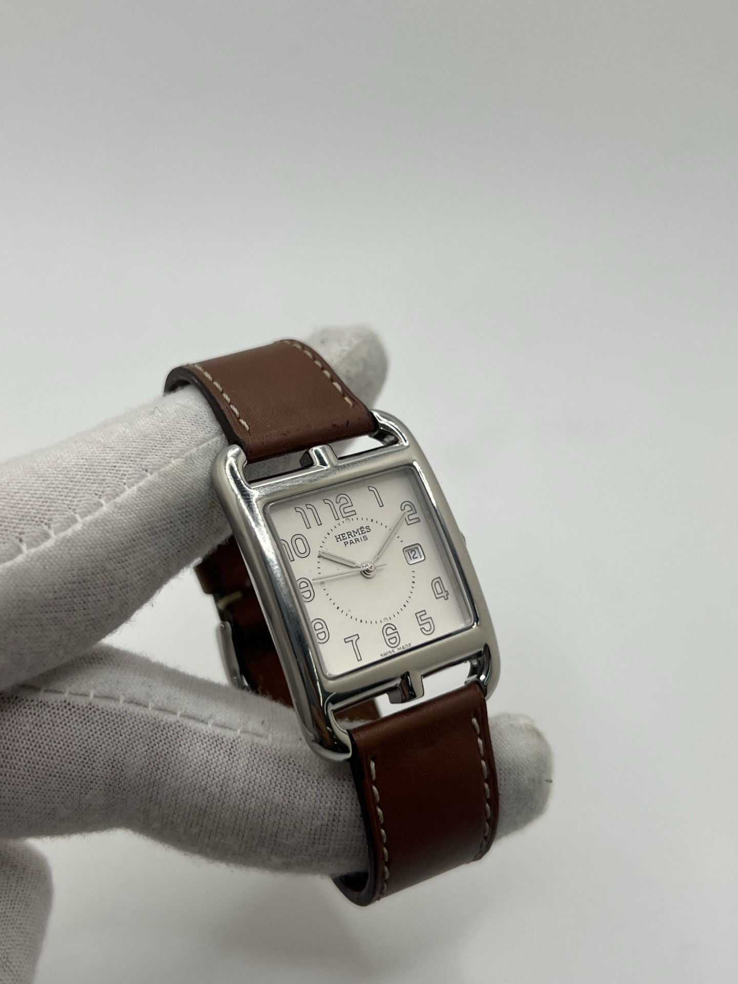 Montre Hermès Cape Cod Grand Modèle en acier inoxydable, boîtier rectangulaire iconique aux lignes élégantes et contemporaines, cadran argenté épuré avec chiffres arabes stylisés et aiguilles fines. Bracelet en cuir signature Hermès offrant confort et raffinement. Mouvement quartz précis. Montre de luxe intemporelle et sophistiquée, idéale pour un porté quotidien ou une tenue habillée, symbole du savoir-faire horloger et du style parisien.