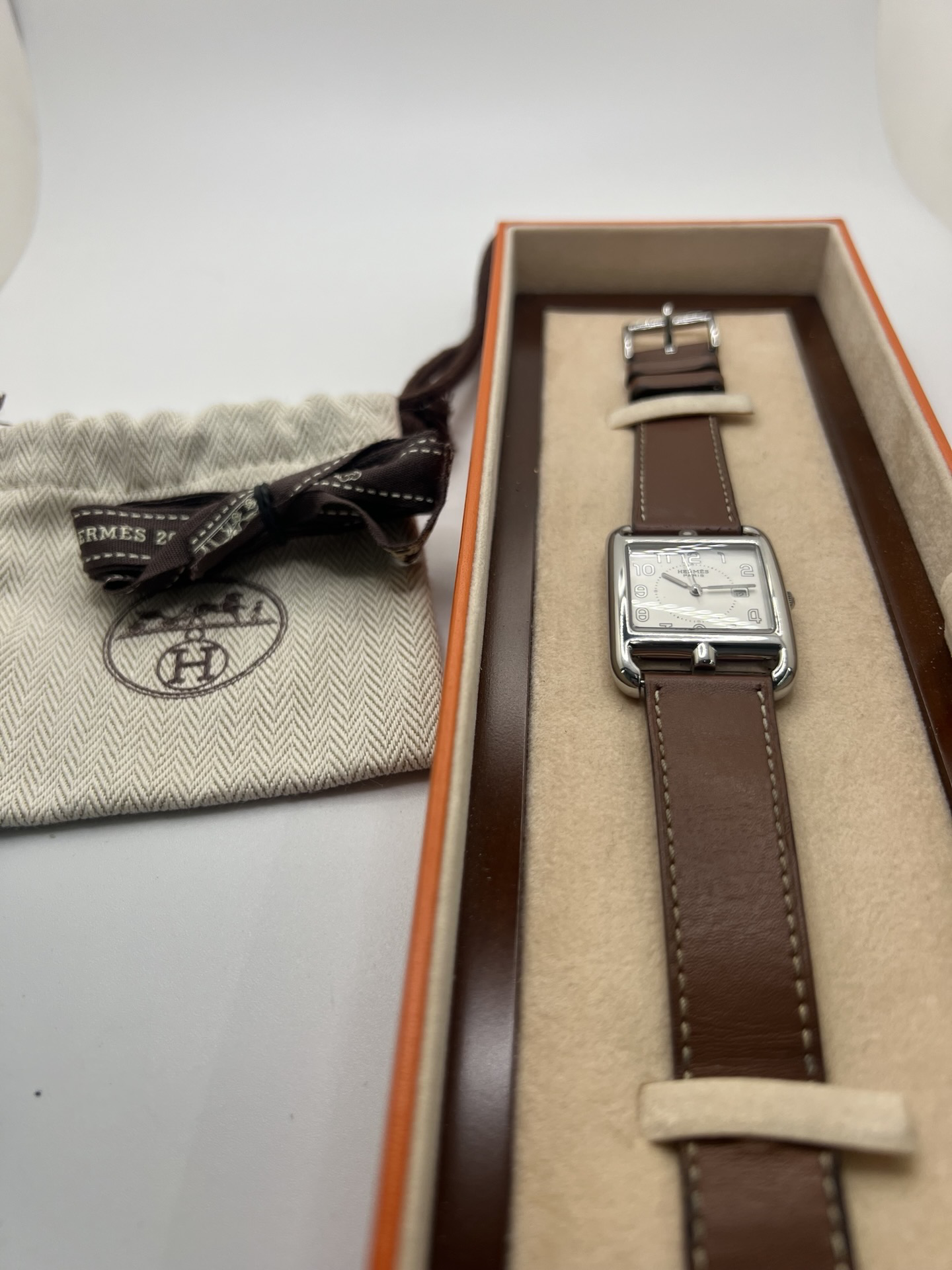 Montre Hermès Cape Cod Grand Modèle en acier inoxydable, boîtier rectangulaire iconique aux lignes élégantes et contemporaines, cadran argenté épuré avec chiffres arabes stylisés et aiguilles fines. Bracelet en cuir signature Hermès offrant confort et raffinement. Mouvement quartz précis. Montre de luxe intemporelle et sophistiquée, idéale pour un porté quotidien ou une tenue habillée, symbole du savoir-faire horloger et du style parisien.