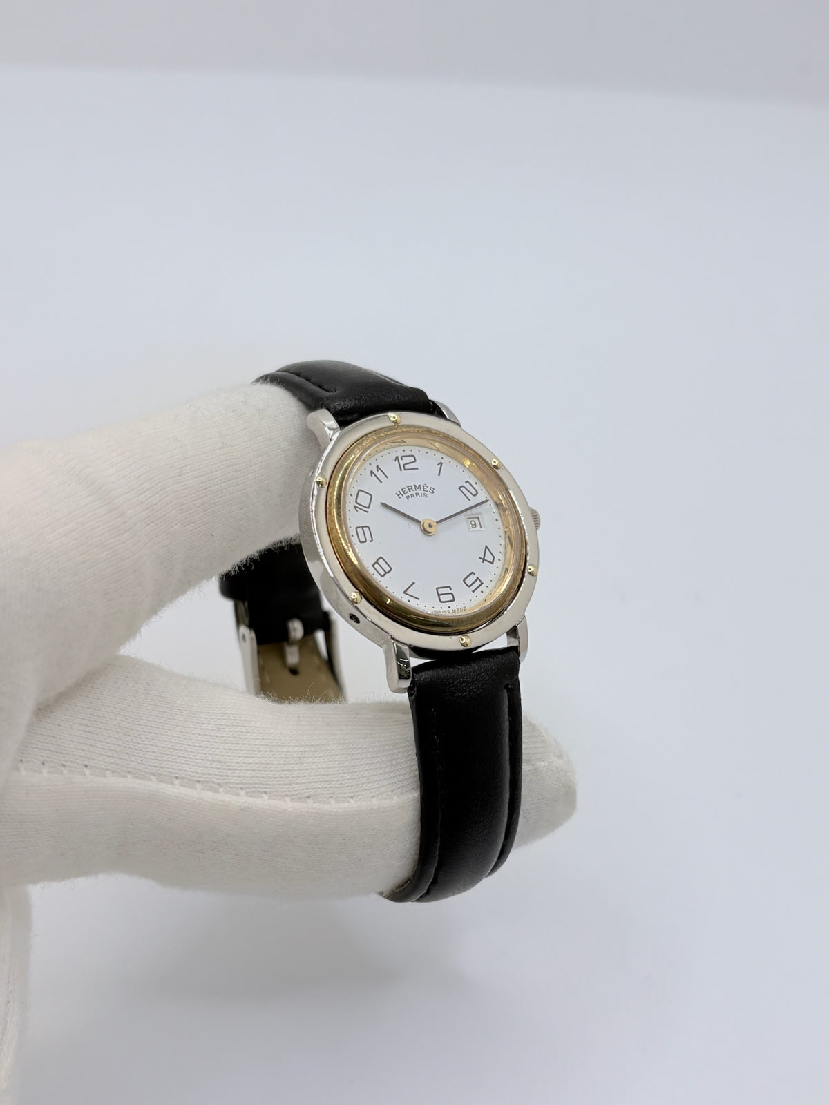Montre Hermès Clipper pour femme en acier, équipée d’un mouvement à quartz. Son boîtier de 30 mm est associé à une lunette en or jaune, un cadran blanc avec chiffres arabes et un verre saphir. Cette montre Hermès Clipper est montée sur un bracelet en cuir de vache noir avec boucle ardillon en acier. Un modèle élégant et intemporel de la collection Clipper, idéal pour les amateurs de montres de luxe.