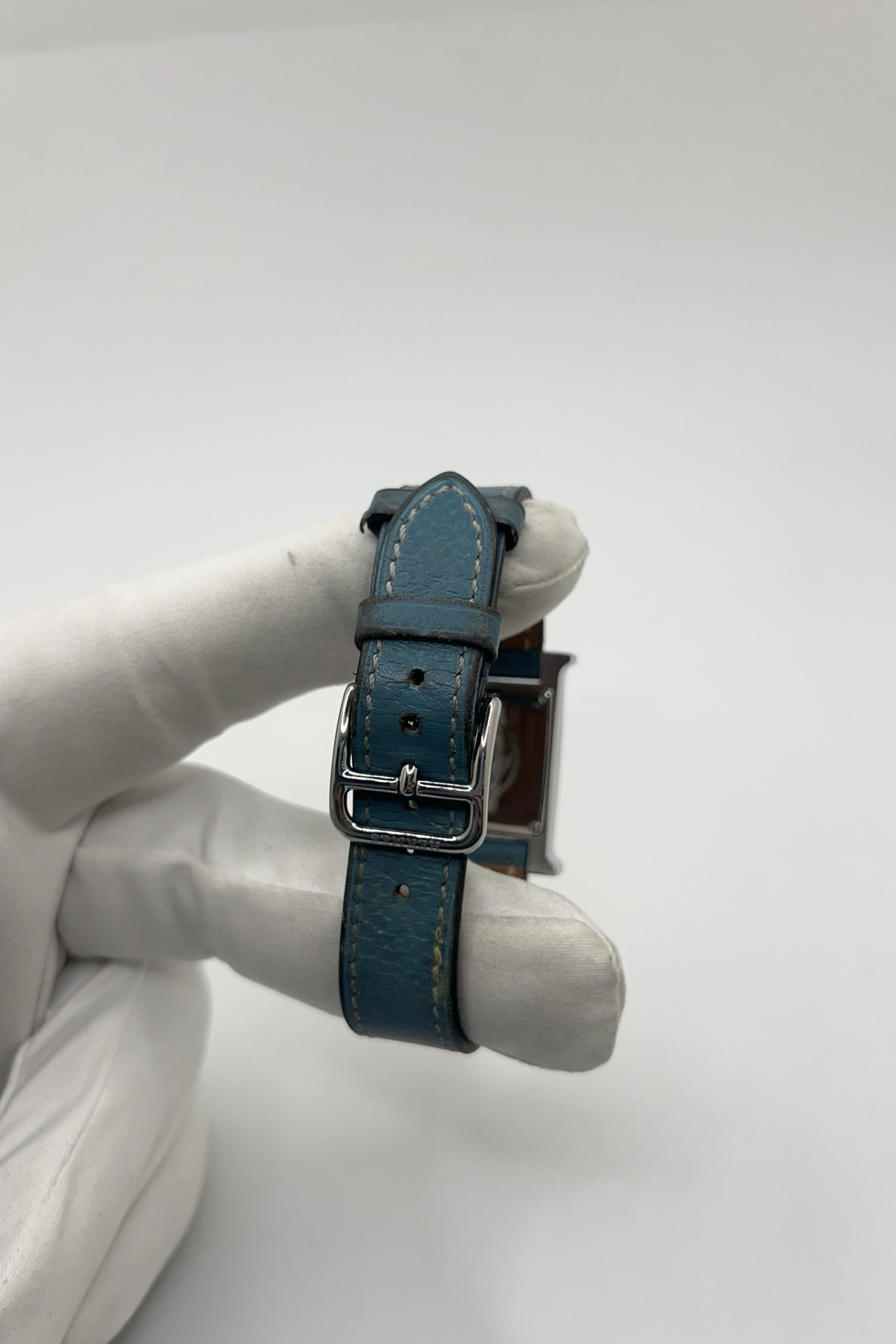 Montre Hermès Heure H HH1.210 en acier avec cadran bleu à chiffres arabes et bracelet cuir Hermès bleu d’origine. Cette montre Hermès femme quartz au design iconique en forme de H incarne l’élégance parisienne et le luxe discret. Modèle Hermès Heure H acier de 21 x 30 mm avec verre saphir, boucle ardillon acier et mouvement quartz fiable. Montre de luxe féminine chic et intemporelle, révisée et livrée avec certificat d’authenticité.