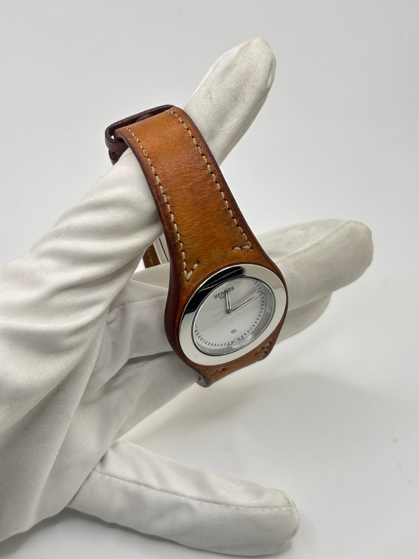 Montre Hermès Harnais HA3.410 en acier avec mouvement quartz, cadran blanc et bracelet en cuir brun. Modèle homme et unisexe au design élégant avec verre saphir et fonction date. Montre d’occasion en très bon état avec légères traces d’usure et micro-rayures discrètes. Format 30 mm idéal pour un style classique et raffiné.

