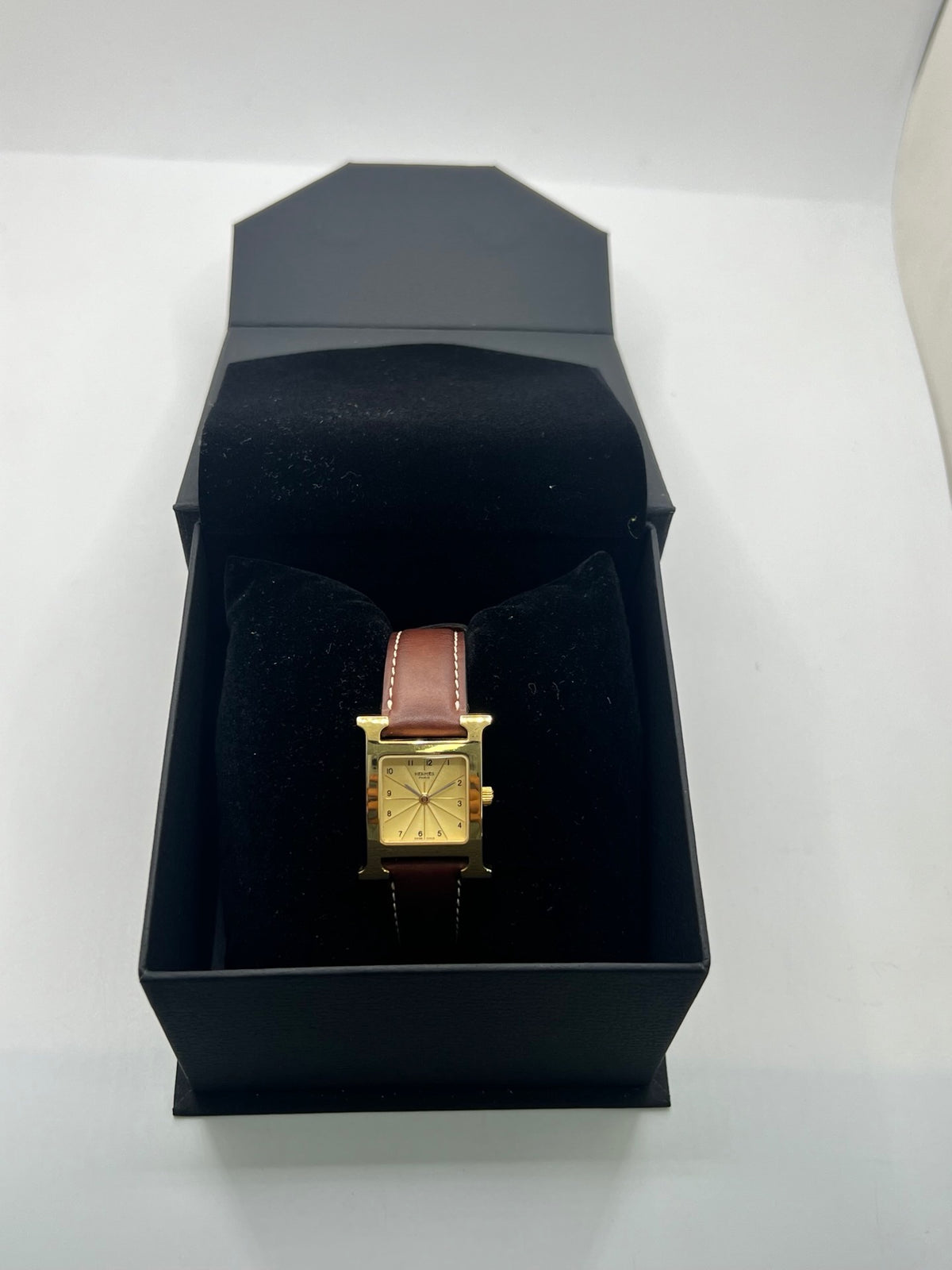 Montre Hermès Heure H HH1.201 pour femme, équipée d’un mouvement quartz et d’un boîtier en acier de 21 mm. Son cadran couleur or est protégé par un verre saphir et accompagné d’un bracelet brun en cuir de vache avec boucle ardillon en acier. Étanche à 3 ATM, cette montre Hermès Heure H se distingue par son célèbre boîtier en forme de H et son design élégant. En très bon état, elle présente de légères traces d’usure.
