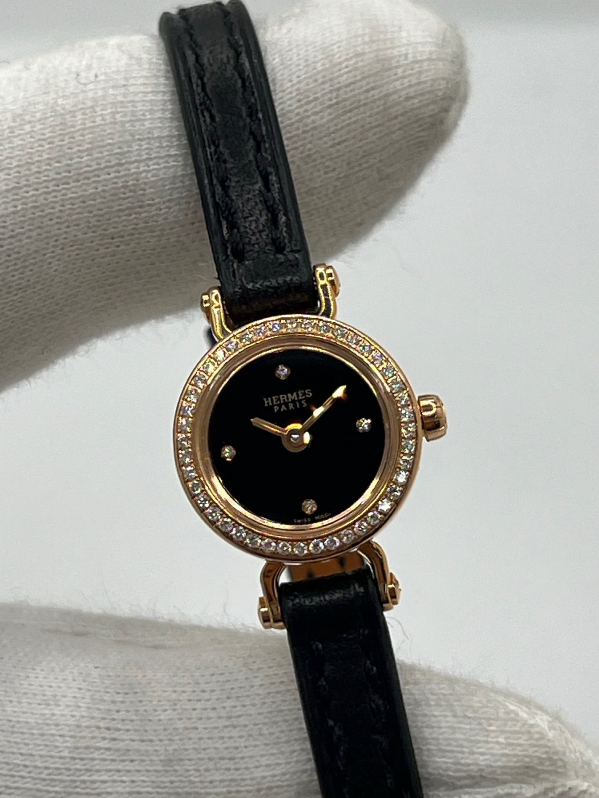 Montre Hermès Faubourg FG4.171 pour femme, dotée d’un élégant boîtier en or rose de 15,5 mm et d’un mouvement quartz. Elle se distingue par son cadran noir sans chiffres, protégé par un verre saphir, et son bracelet en cuir noir avec boucle ardillon en or rose. Cette montre de luxe Hermès associe raffinement, élégance et discrétion. Modèle d’occasion en très bon état, révisé en interne en octobre 2026 et livré avec son coffret d’origine.