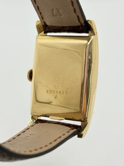 Montre Jaeger-LeCoultre Classic 9012 vintage à remontage manuel, datant approximativement de 1960. Son boîtier rectangulaire en or jaune de 37 × 23 mm est équipé d’un verre Plexiglas et d’un élégant cadran or à index bâtons. Cette montre Jaeger-LeCoultre est montée sur un bracelet brun en cuir de crocodile avec boucle ardillon en acier. En très bon état, elle présente de légères traces d’usure et est proposée avec son coffret d’origine.