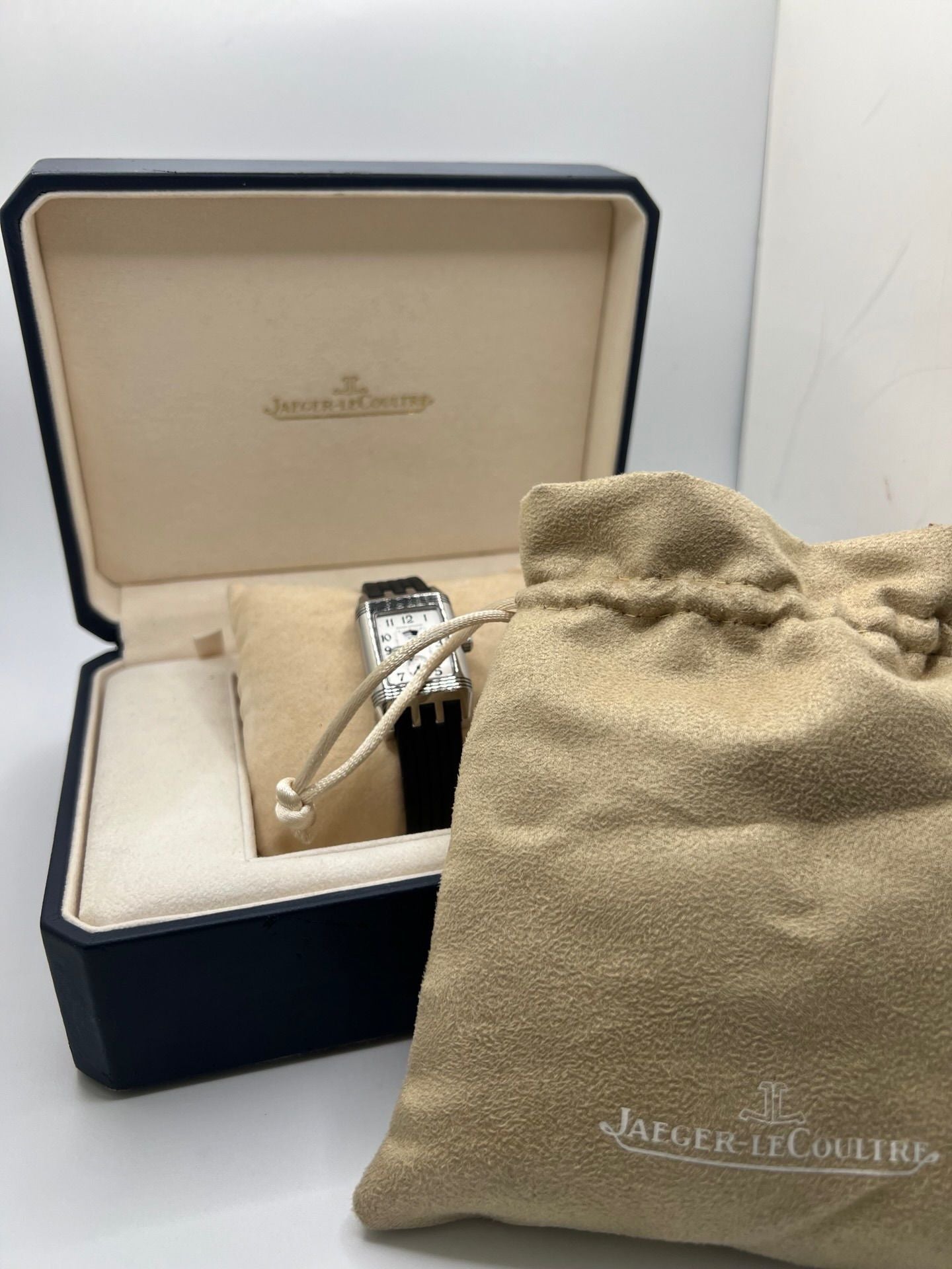 Montre Reverso Duetto référence 296.8.74 en acier, format rectangulaire, équipée d’un mouvement à remontage manuel. Modèle pour femme avec cadran blanc à chiffres arabes et verre saphir. Brace­let en caoutchouc noir avec boucle double plis. Pièce d’occasion en très bon état, présentant de légères traces d’usure discrètes.