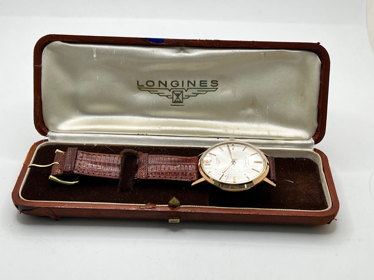 Montre Longines Flagship 2407 vintage en très bon état, datant approximativement de 1962, avec mouvement automatique calibre 341. Son boîtier de 35 mm en or rose est associé à un cadran argent à index bâtons et un verre Plexiglas. Cette Longines Flagship possède un bracelet en cuir de lézard brun avec boucle ardillon en acier. Elle dispose également d’une fonction date et d’un design élégant et intemporel.