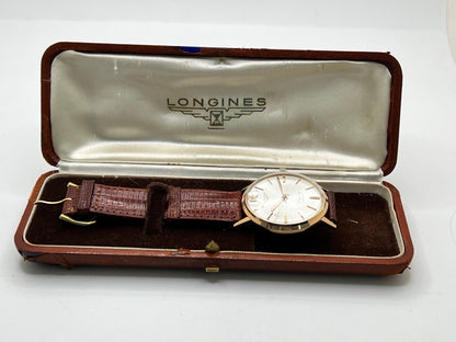 Montre Longines Flagship 2407 vintage en très bon état, datant approximativement de 1962, avec mouvement automatique calibre 341. Son boîtier de 35 mm en or rose est associé à un cadran argent à index bâtons et un verre Plexiglas. Cette Longines Flagship possède un bracelet en cuir de lézard brun avec boucle ardillon en acier. Elle dispose également d’une fonction date et d’un design élégant et intemporel.