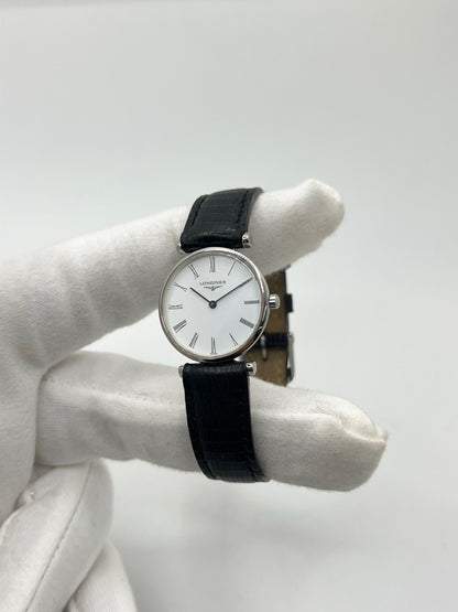 Montre Longines La Grande Classique L4.209.4 pour femme en acier avec bracelet en cuir de lézard noir. Ce modèle à mouvement quartz est doté d'un boîtier de 24 mm, d'un cadran blanc épuré sans chiffres, d'une lunette en acier et d'un verre saphir. Élégante et intemporelle, cette montre de luxe d'occasion est en très bon état avec de légères traces d'usure. Son design raffiné en fait un choix idéal pour un usage quotidien ou une collection horlogère.