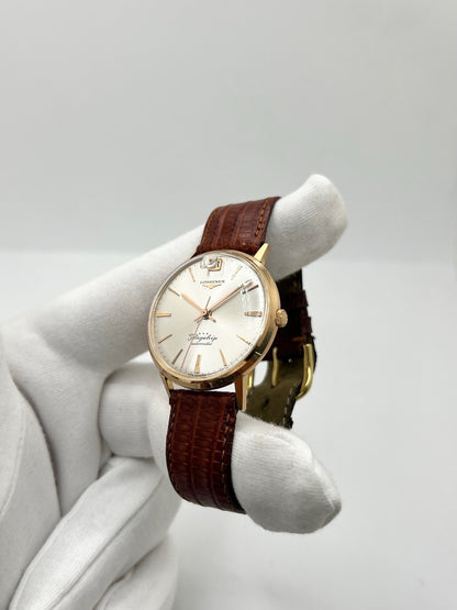 Montre Longines Flagship 2407 vintage en très bon état, datant approximativement de 1962, avec mouvement automatique calibre 341. Son boîtier de 35 mm en or rose est associé à un cadran argent à index bâtons et un verre Plexiglas. Cette Longines Flagship possède un bracelet en cuir de lézard brun avec boucle ardillon en acier. Elle dispose également d’une fonction date et d’un design élégant et intemporel.