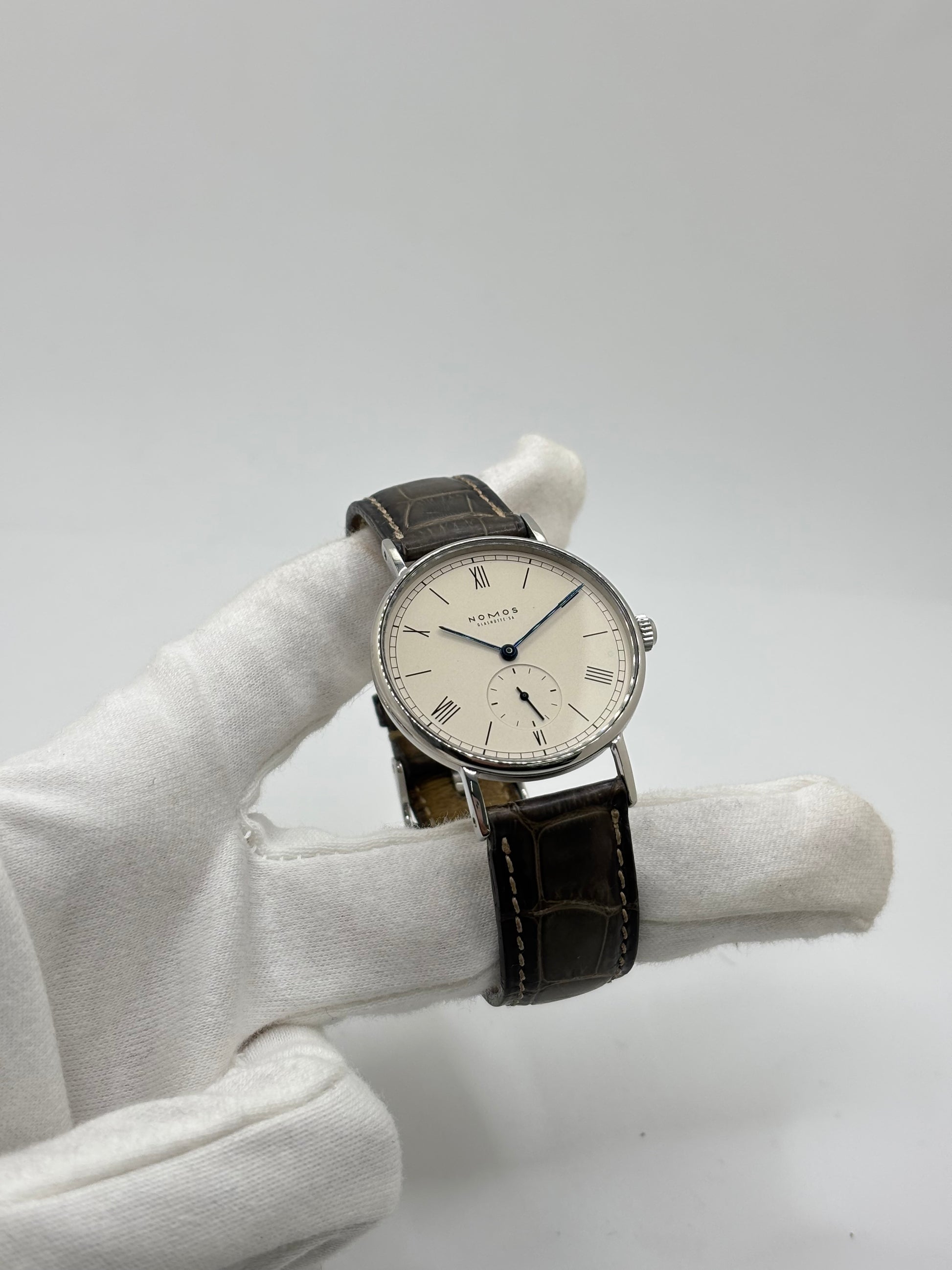 Montre Nomos Glashütte Ludwig 205 en acier avec boîtier de 37,5 mm, mouvement à remontage manuel offrant 43 heures de réserve de marche et cadran blanc à chiffres romains. Équipée d'un verre saphir, d'un bracelet en cuir noir, d'une petite seconde, d'un fond transparent et d'aiguilles en acier bleui, cette montre de luxe d'occasion est en très bon état avec de légères traces d'usure. Un modèle élégant au style intemporel, idéal pour les amateurs d'horlogerie.
