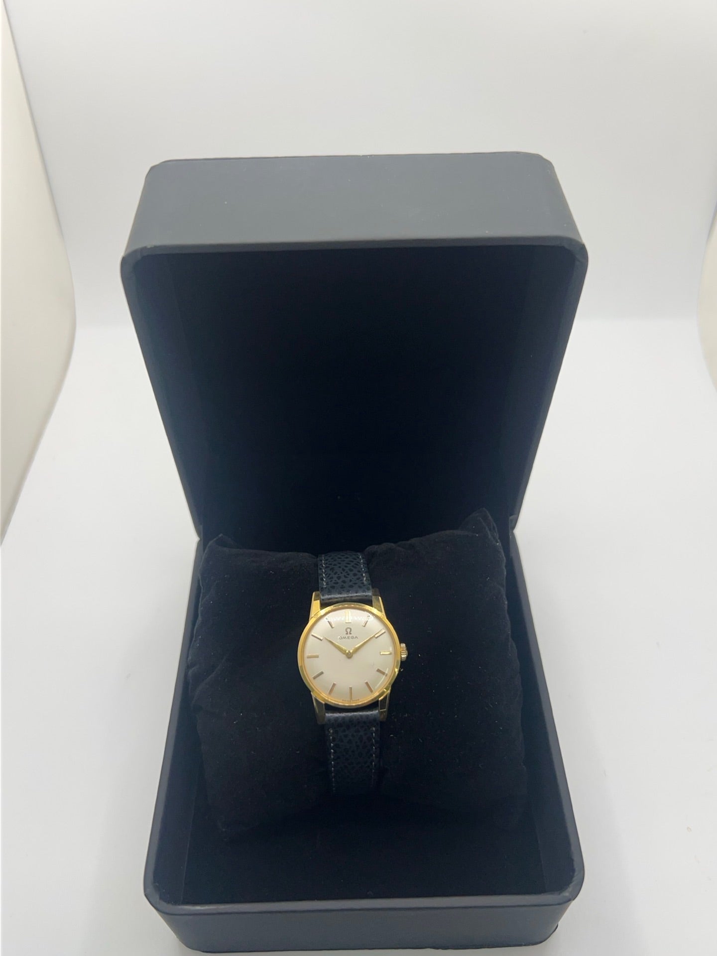 Montre femme Omega Classic vintage de 1961 en plaqué or, équipée d’un mouvement à remontage manuel. Boîtier de 25 mm avec cadran blanc à index bâtons sous verre plexiglas. Bracelet en cuir noir avec boucle ardillon en acier. Montre d’occasion en très bon état, présentant de légères micro-rayures non perceptibles au toucher. Révisée en avril 2026, sans coffret ni papiers d’origine, disponible en stock à Paris.
