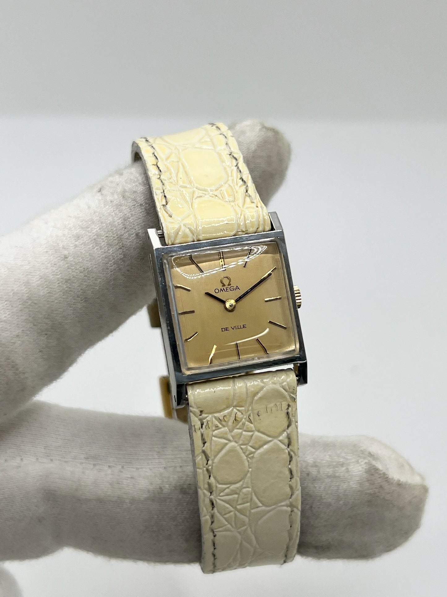 Montre Omega De Ville 511.087 vintage pour femme en acier, fabriquée en 1966. Cette montre élégante est dotée d'un cadran champagne avec index bâtons, d'un mouvement à remontage manuel calibre 620 et d'un verre en plexiglas. Elle est montée sur un bracelet en cuir beige avec boucle ardillon en acier. Son format de 19,5 mm lui confère une allure raffinée et intemporelle. Montre de collection en très bon état d'occasion, révisée et prête à être portée.