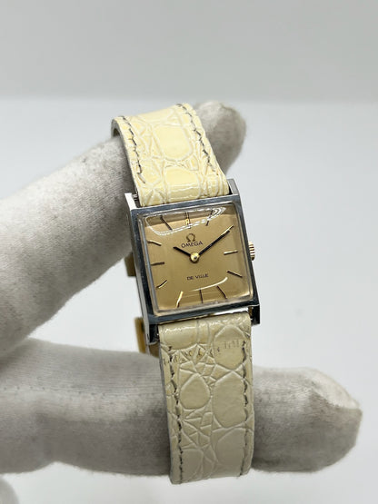 Montre Omega De Ville 511.087 vintage pour femme en acier, fabriquée en 1966. Cette montre élégante est dotée d'un cadran champagne avec index bâtons, d'un mouvement à remontage manuel calibre 620 et d'un verre en plexiglas. Elle est montée sur un bracelet en cuir beige avec boucle ardillon en acier. Son format de 19,5 mm lui confère une allure raffinée et intemporelle. Montre de collection en très bon état d'occasion, révisée et prête à être portée.