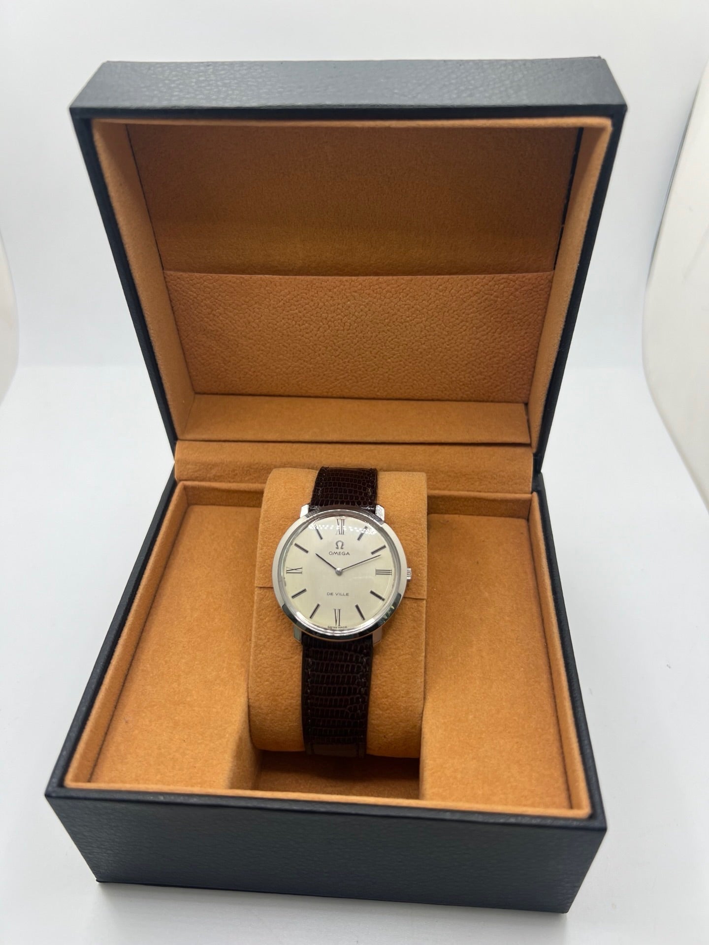 Montre Omega De Ville vintage référence 111.077 en acier, fabriquée en 1969. Ce modèle à remontage manuel est doté d'un cadran argent avec chiffres romains, d'un verre en plexiglas et d'un boîtier de 33 mm. Le bracelet en cuir noir avec boucle ardillon en acier complète son style classique et intemporel. Cette montre d'occasion révisée séduit les amateurs d'horlogerie vintage et de montres Omega de collection.
