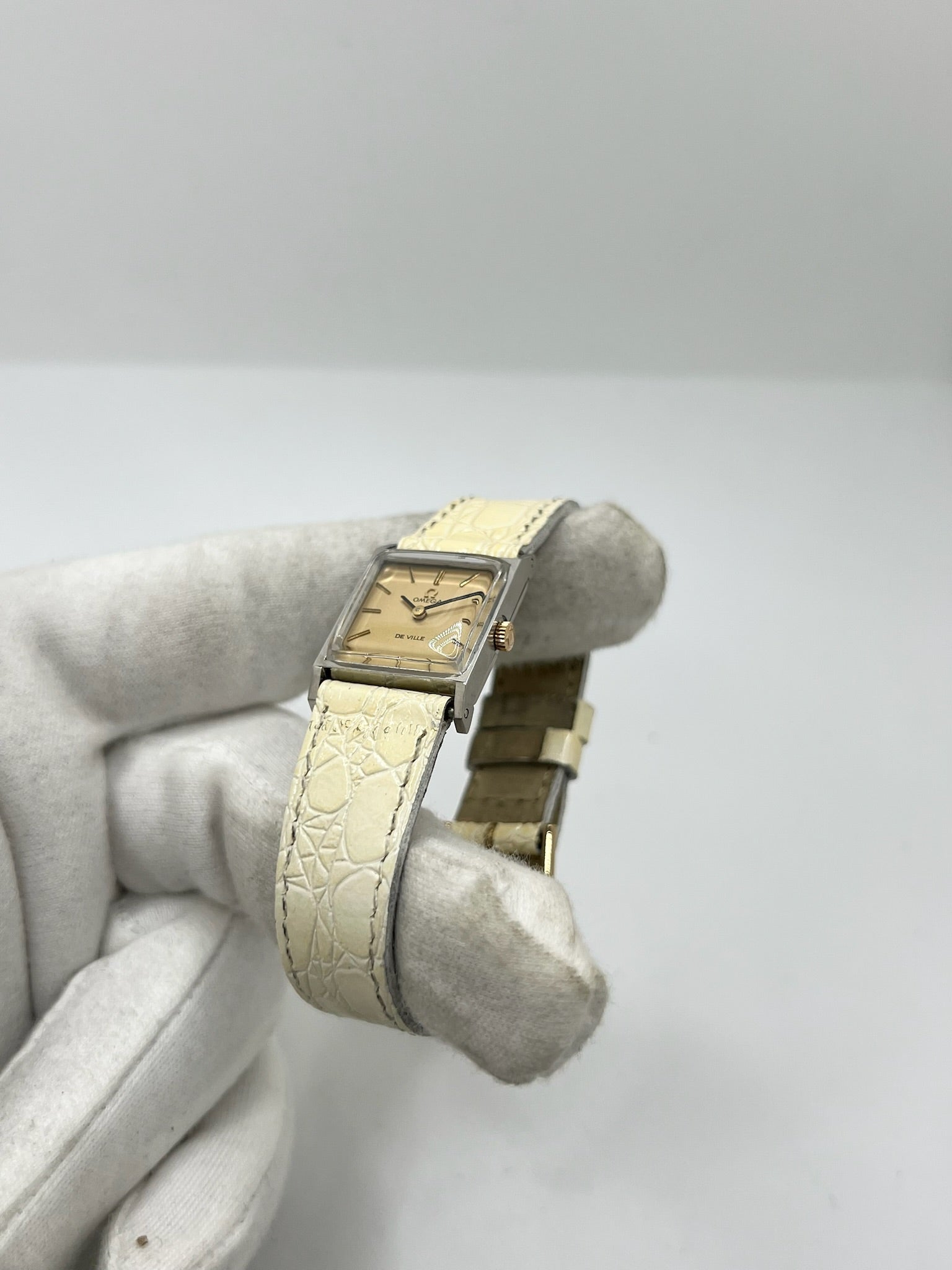 Montre Omega De Ville 511.087 vintage pour femme en acier, fabriquée en 1966. Cette montre élégante est dotée d'un cadran champagne avec index bâtons, d'un mouvement à remontage manuel calibre 620 et d'un verre en plexiglas. Elle est montée sur un bracelet en cuir beige avec boucle ardillon en acier. Son format de 19,5 mm lui confère une allure raffinée et intemporelle. Montre de collection en très bon état d'occasion, révisée et prête à être portée.