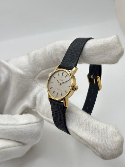 Montre Omega De Ville vintage référence 511.0508 pour femme, datant de 1967, avec boîtier en acier de 24 mm et cadran gris à index bâtons. Cette montre à remontage manuel est équipée du calibre Omega 625 à 17 rubis et est montée sur un bracelet en cuir noir avec boucle ardillon en acier. Révisée et en très bon état, elle présente de légères traces d'usure conformes à son âge. Une montre de collection au design élégant, idéale pour les amateurs d'horlogerie vintage.