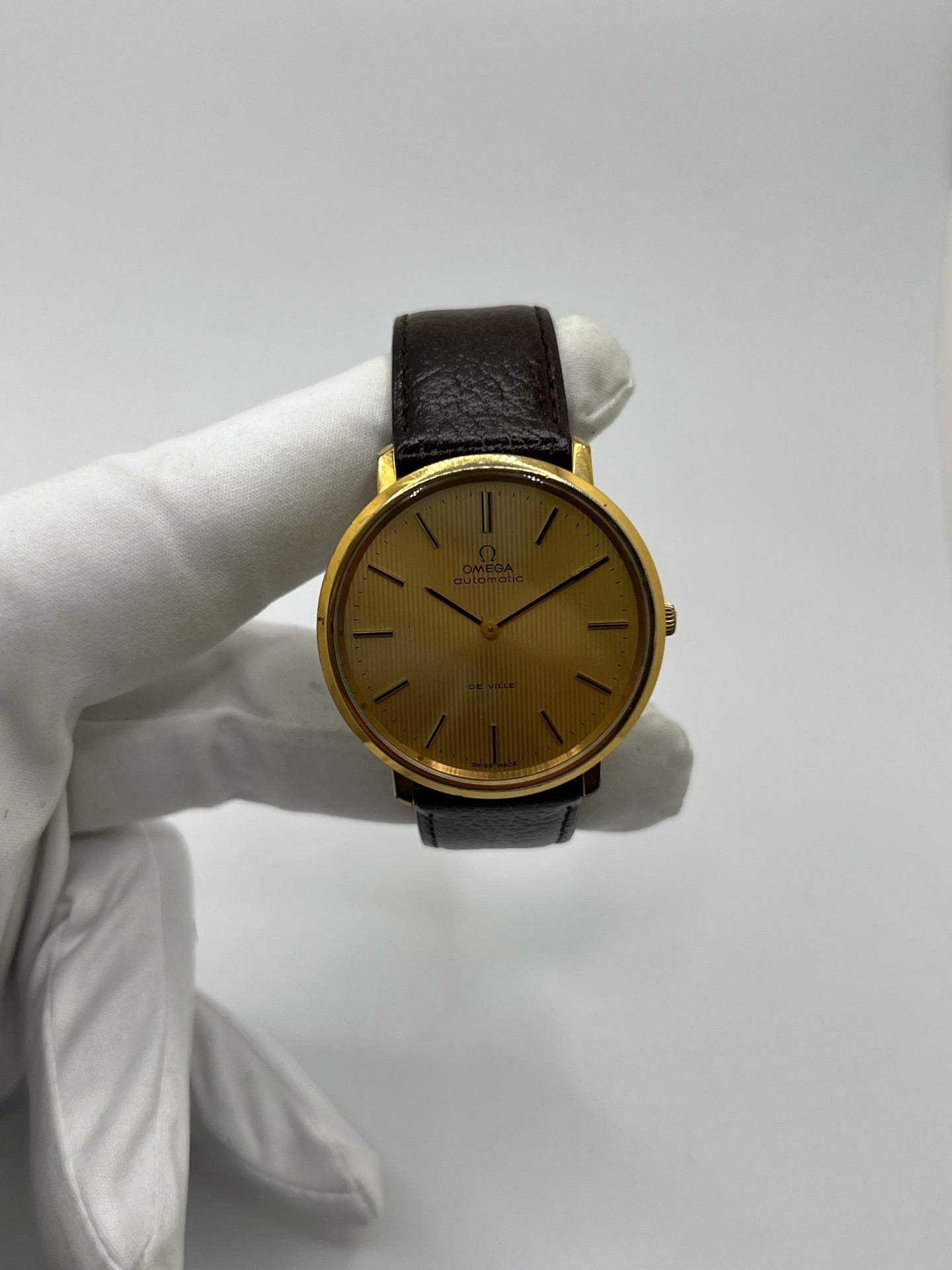 Montre Omega De Ville référence 151.0039 vintage de 1973 en acier avec mouvement automatique calibre 711, cadran doré et bracelet en cuir noir. Ce modèle homme ou unisexe de 35,5 mm présente un design élégant et intemporel. Montre d’occasion en très bon état, révisée en interne le 13 mars 2026, avec légères traces d’usure discrètes. Pièce classique de collection sans coffret ni papiers d’origine.