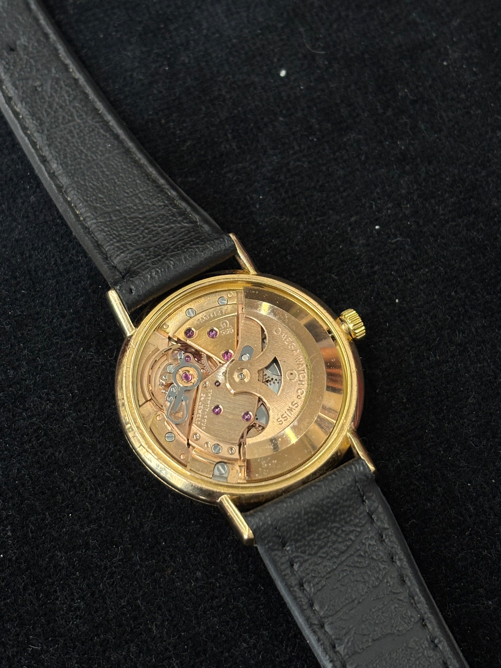 Montre Omega Genève vintage en or jaune 18 carats, référence 162.3009, équipée d’un mouvement automatique calibre 565. Boîtier de 35 mm avec cadran doré à index bâtons et verre plexiglas. Bracelet en cuir noir avec boucle acier. Modèle homme/unisexe fabriqué en 1967, au style classique et élégant. Montre d’occasion avec traces d’usure visibles, révisée en avril 2026, idéale pour collectionneurs et amateurs d’horlogerie ancienne.