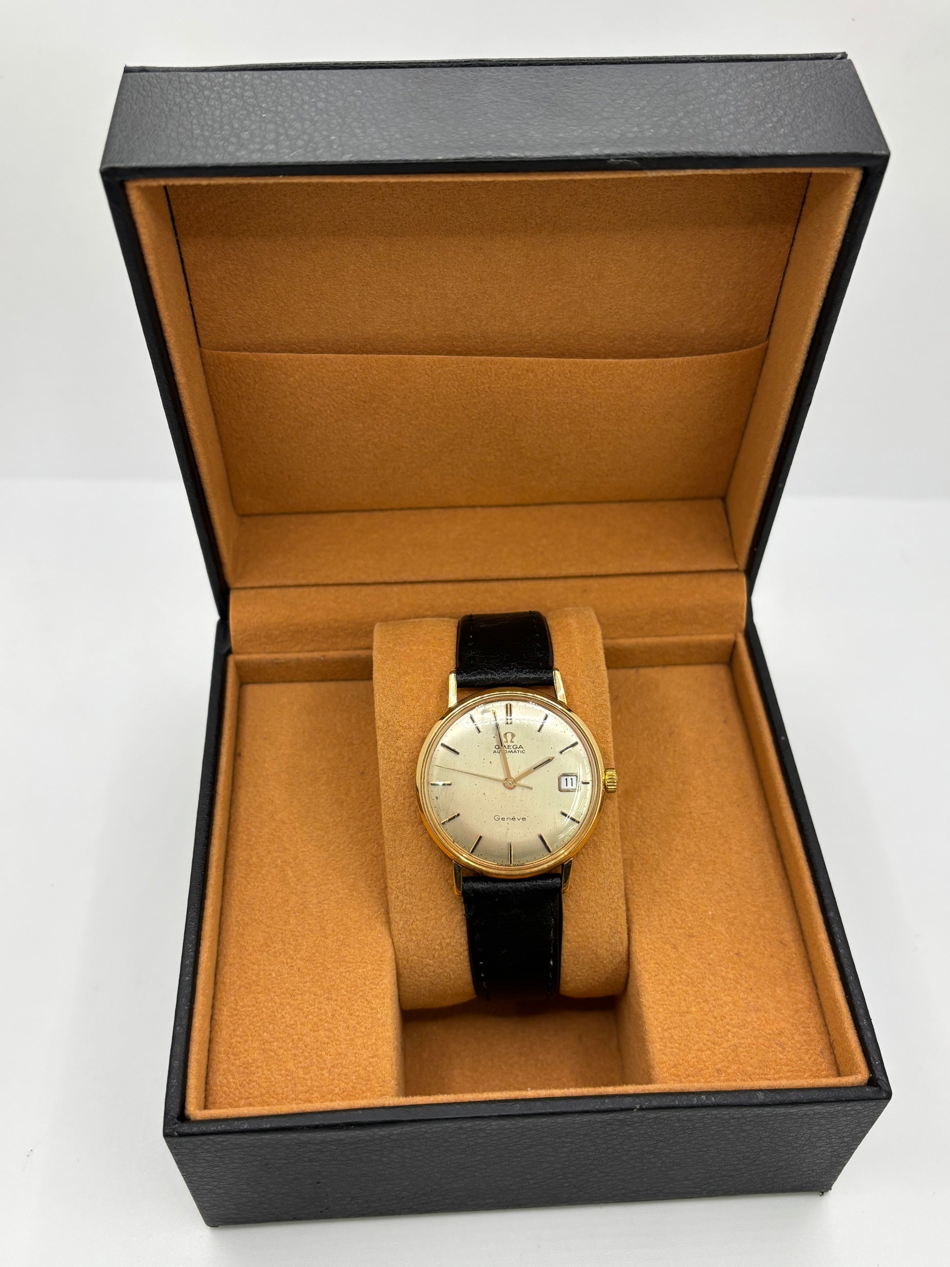Montre Omega Genève vintage en or jaune 18 carats, référence 162.3009, équipée d’un mouvement automatique calibre 565. Boîtier de 35 mm avec cadran doré à index bâtons et verre plexiglas. Bracelet en cuir noir avec boucle acier. Modèle homme/unisexe fabriqué en 1967, au style classique et élégant. Montre d’occasion avec traces d’usure visibles, révisée en avril 2026, idéale pour collectionneurs et amateurs d’horlogerie ancienne.