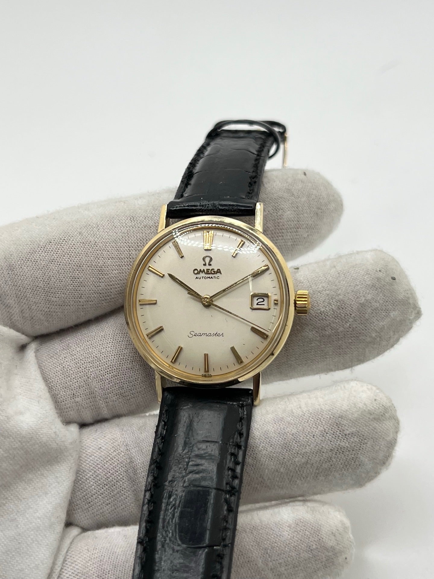 Montre Omega Seamaster DeVille vintage de 1961 en or jaune 14 carats, équipée d’un mouvement automatique calibre 560. Boîtier rond de 34 mm avec verre plexiglas, cadran champagne à index bâtons et date. Bracelet en cuir de crocodile noir avec boucle en or. Montre homme élégante et intemporelle, en bon état avec traces d’usure, récemment révisée, idéale pour collection ou usage quotidien.