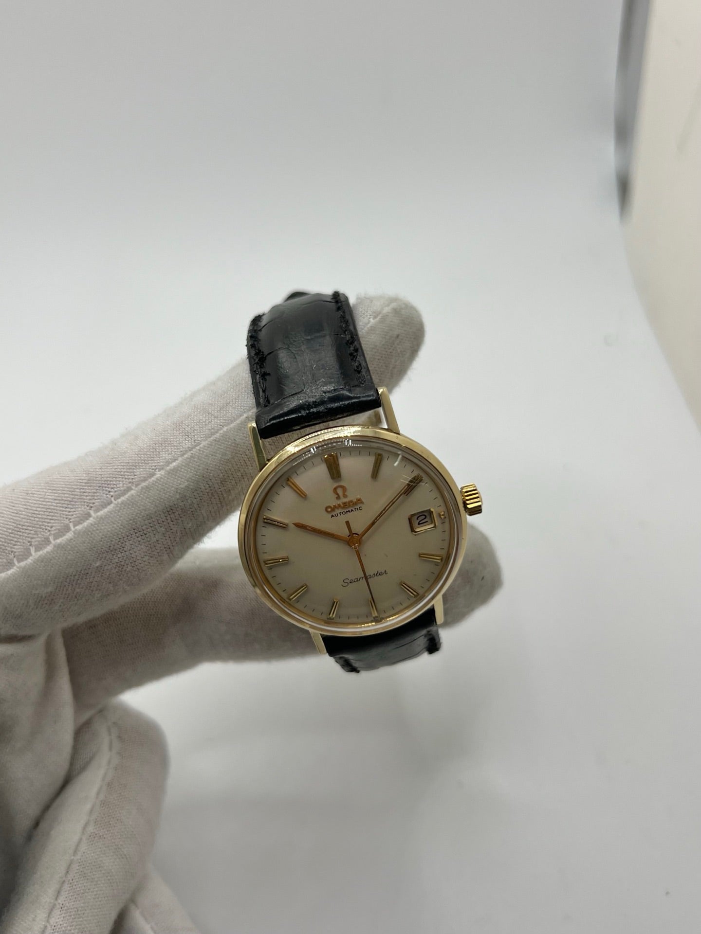 Montre Omega Seamaster DeVille vintage de 1961 en or jaune 14 carats, équipée d’un mouvement automatique calibre 560. Boîtier rond de 34 mm avec verre plexiglas, cadran champagne à index bâtons et date. Bracelet en cuir de crocodile noir avec boucle en or. Montre homme élégante et intemporelle, en bon état avec traces d’usure, récemment révisée, idéale pour collection ou usage quotidien.