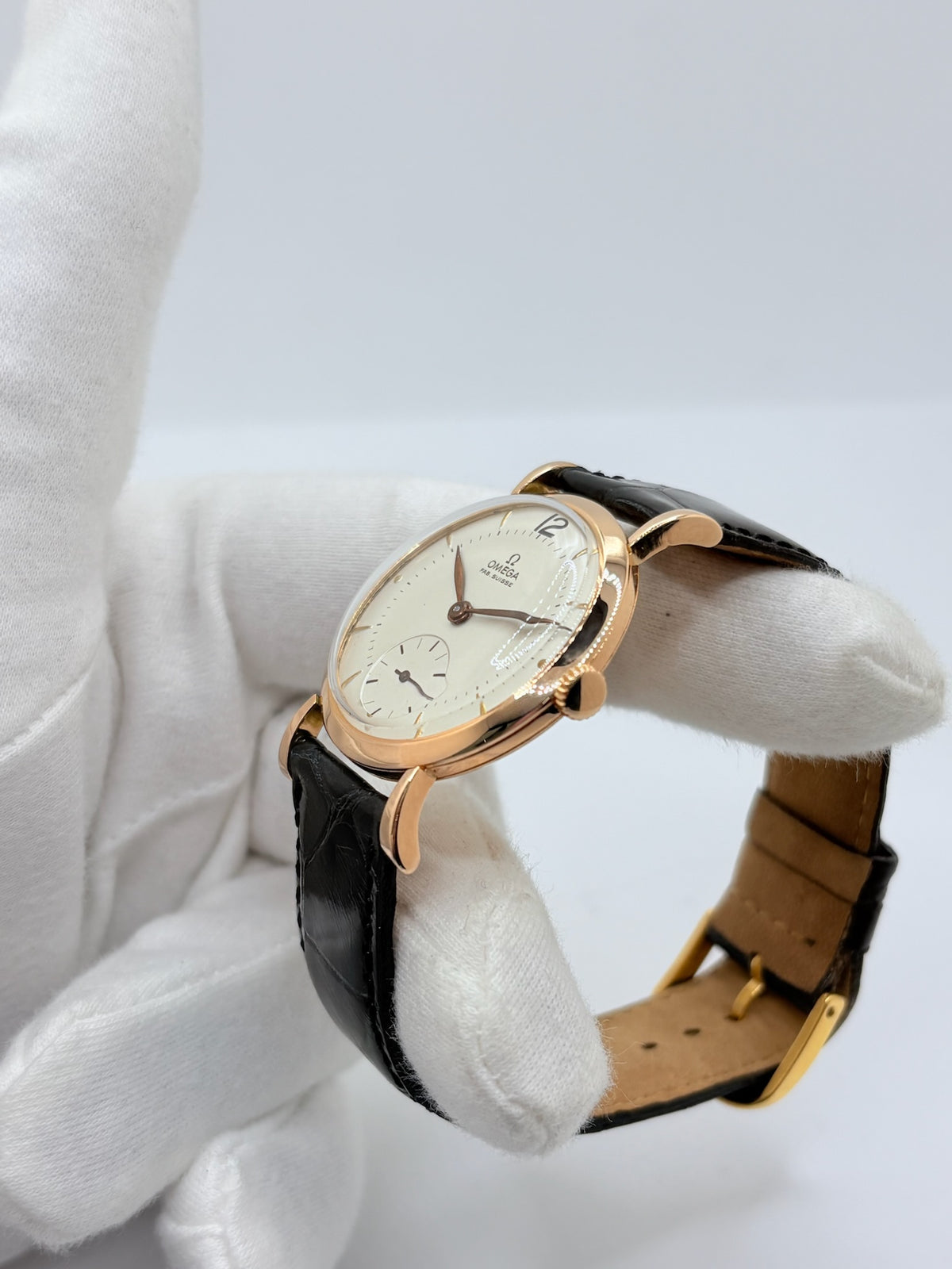 Montre Omega Vintage équipée du célèbre calibre mécanique 30T2 à remontage manuel. Cette montre ancienne, datant approximativement de 1948, présente un boîtier en or rose de 33 mm et un élégant cadran blanc à index bâtons. Son bracelet en cuir de crocodile noir complète son esthétique classique et intemporelle. Cette Omega Vintage calibre 30T2 incarne le charme d’une montre de collection, alliant savoir-faire horloger, élégance et authenticité.