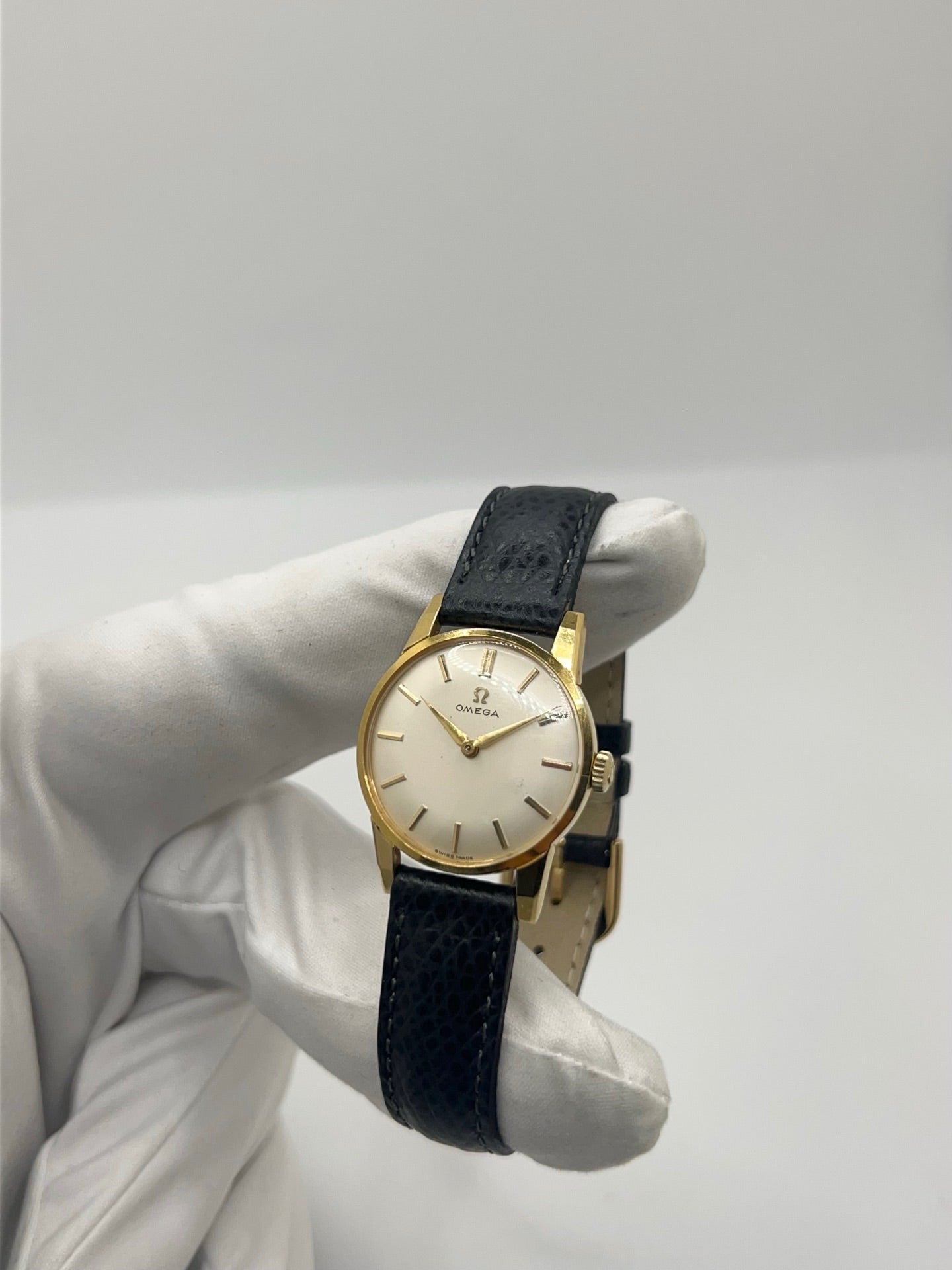Montre femme Omega Classic vintage de 1961 en plaqué or, équipée d’un mouvement à remontage manuel. Boîtier de 25 mm avec cadran blanc à index bâtons sous verre plexiglas. Bracelet en cuir noir avec boucle ardillon en acier. Montre d’occasion en très bon état, présentant de légères micro-rayures non perceptibles au toucher. Révisée en avril 2026, sans coffret ni papiers d’origine, disponible en stock à Paris.
