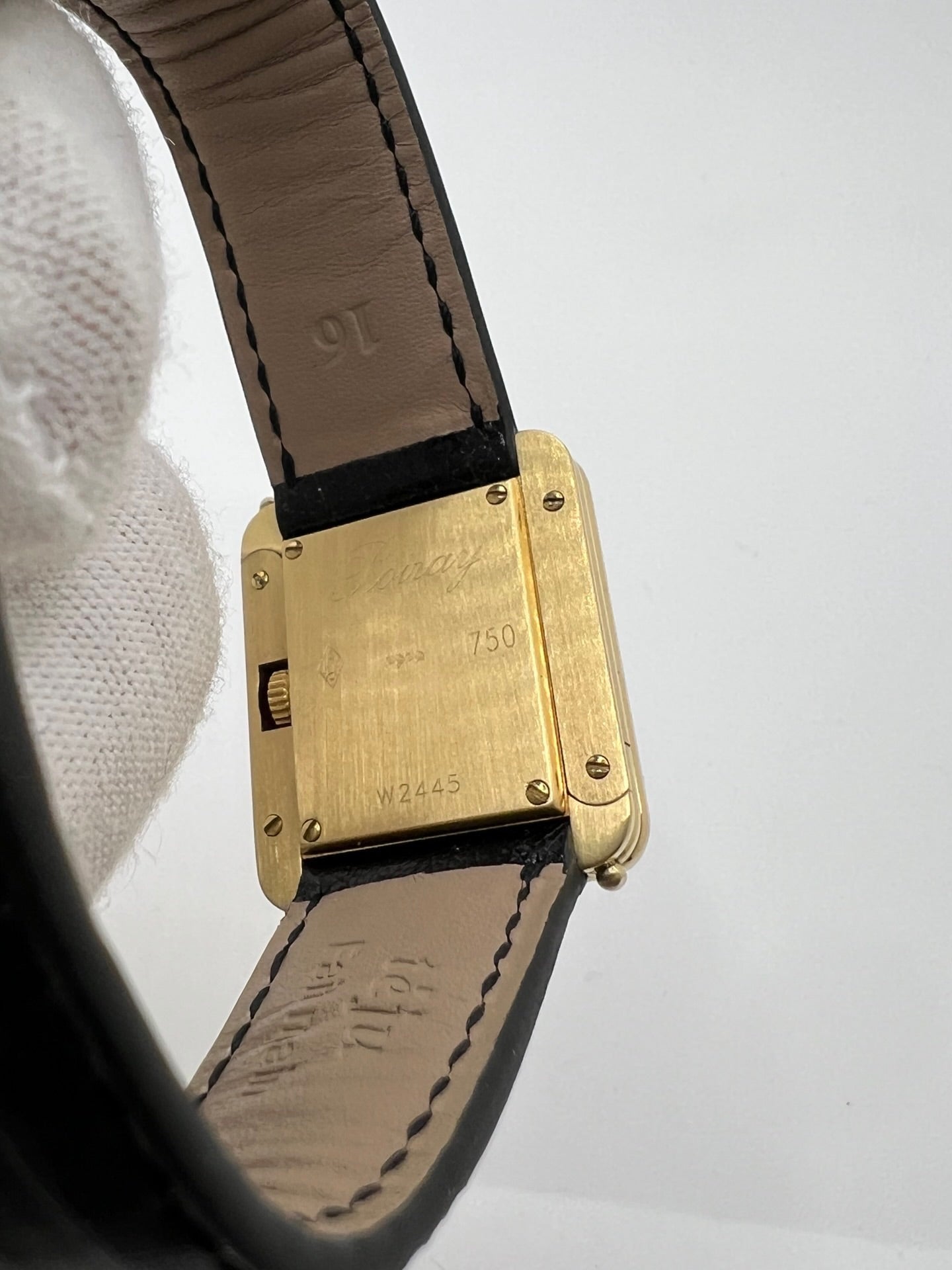 Montre femme Poiray Ma Première en or jaune 18K avec boîtier rectangulaire 22 x 26 mm, cadran doré sans chiffres et verre saphir. Modèle élégant équipé d’un mouvement quartz, bracelet en cuir noir et boucle en acier. Pièce d’occasion en très bon état présentant de légères traces d’usure non perceptibles. Montre raffinée, révisée récemment, idéale pour un style intemporel.