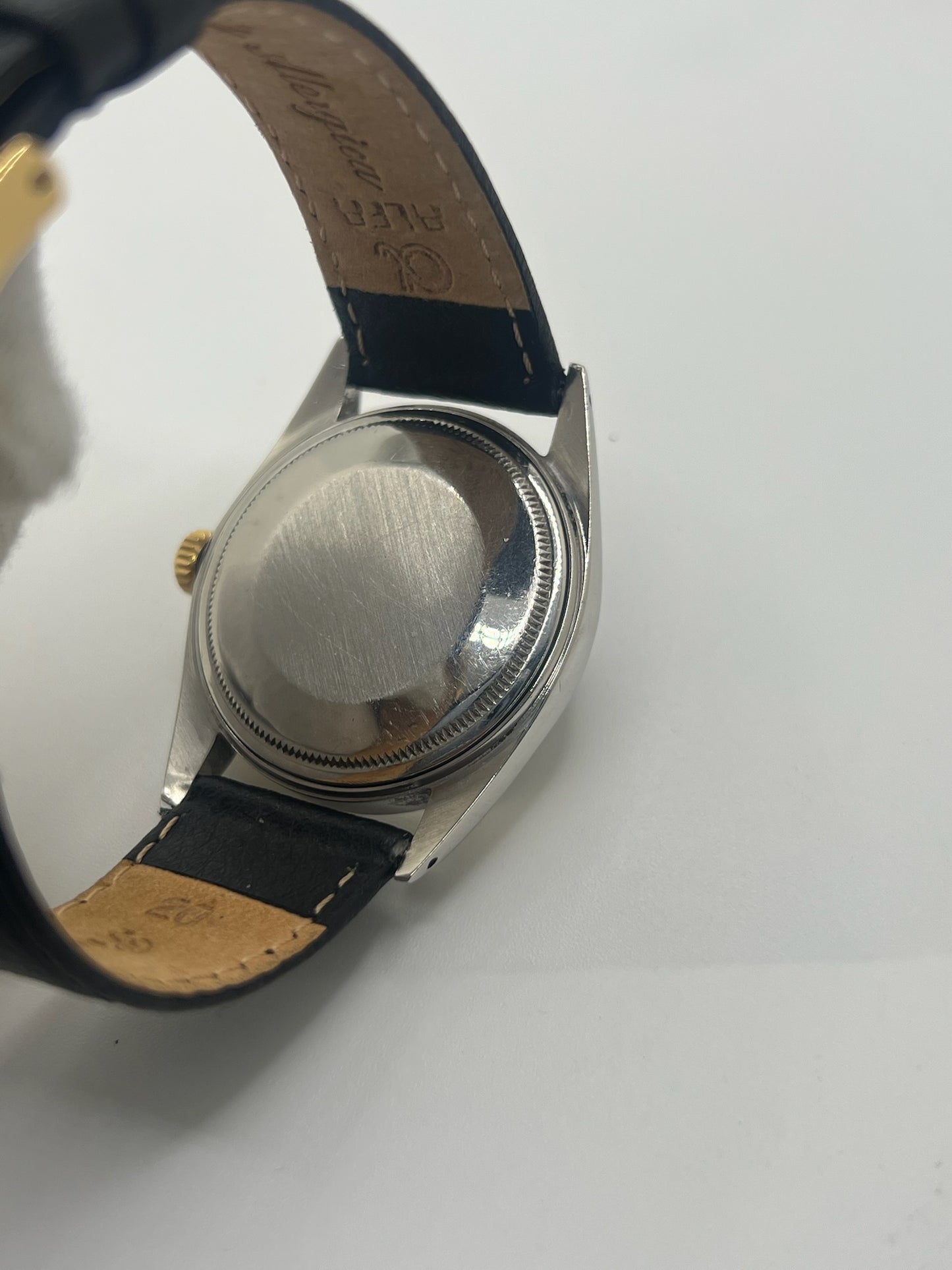 Montre Rolex Datejust automatique vintage de 36 mm en acier avec lunette en or jaune, cadran noir épuré sans chiffres et affichage de la date à 3 heures. Boîtier élégant protégé par un verre plexiglas, étanche jusqu’à 10 ATM. Bracelet en cuir noir avec boucle en acier. Mouvement mécanique à remontage automatique offrant environ 40 heures de réserve de marche. Modèle des années 1960, en très bon état, présentant de légères traces d’usure superficielles.