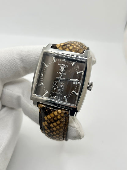 Montre TAG Heuer Monaco Calibre 6 WW2115 pour homme, équipée d’un mouvement automatique offrant une réserve de marche de 42 heures et du calibre 6 doté de 27 pierres. Son boîtier en acier de 37 mm accueille un cadran brun au style élégant et distinctif. Cette TAG Heuer Monaco est montée sur un bracelet en cuir de serpent avec boucle déployante en acier. Dotée d’un affichage de la date, elle allie design emblématique et savoir-faire horloger. Vendue avec son coffret d’origine, en très bon état.