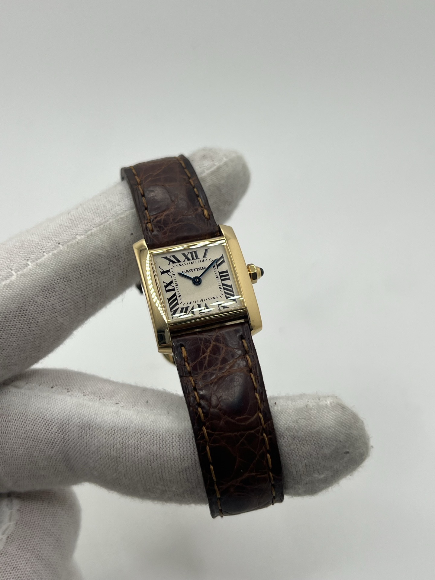 Montre Cartier Tank Française référence 1820 en or jaune 18K, petit modèle pour femme, boîtier rectangulaire emblématique aux lignes droites et élégantes, cadran blanc avec chiffres romains noirs, minuterie chemin de fer et aiguilles bleuies en forme de glaive. Bracelet intégré en acier avec boucle déployante. Mouvement quartz précis. Montre de luxe intemporelle, raffinée et iconique, idéale pour un porté quotidien ou une tenue habillée.