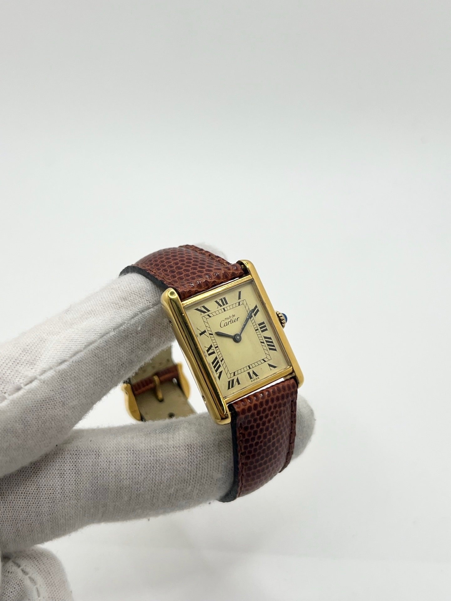 Montre Cartier Tank Must Vermeil, boîtier argent 31 x 23 mm, mouvement à remontage manuel Cartier 78-1 avec réserve de marche de 44 h et 17 pierres. Cadran blanc à chiffres romains, verre minéral. Bracelet en cuir de lézard brun avec boucle en argent. État d’occasion très bon avec légères rayures, alliant élégance intemporelle et design iconique pour homme ou unisexe.