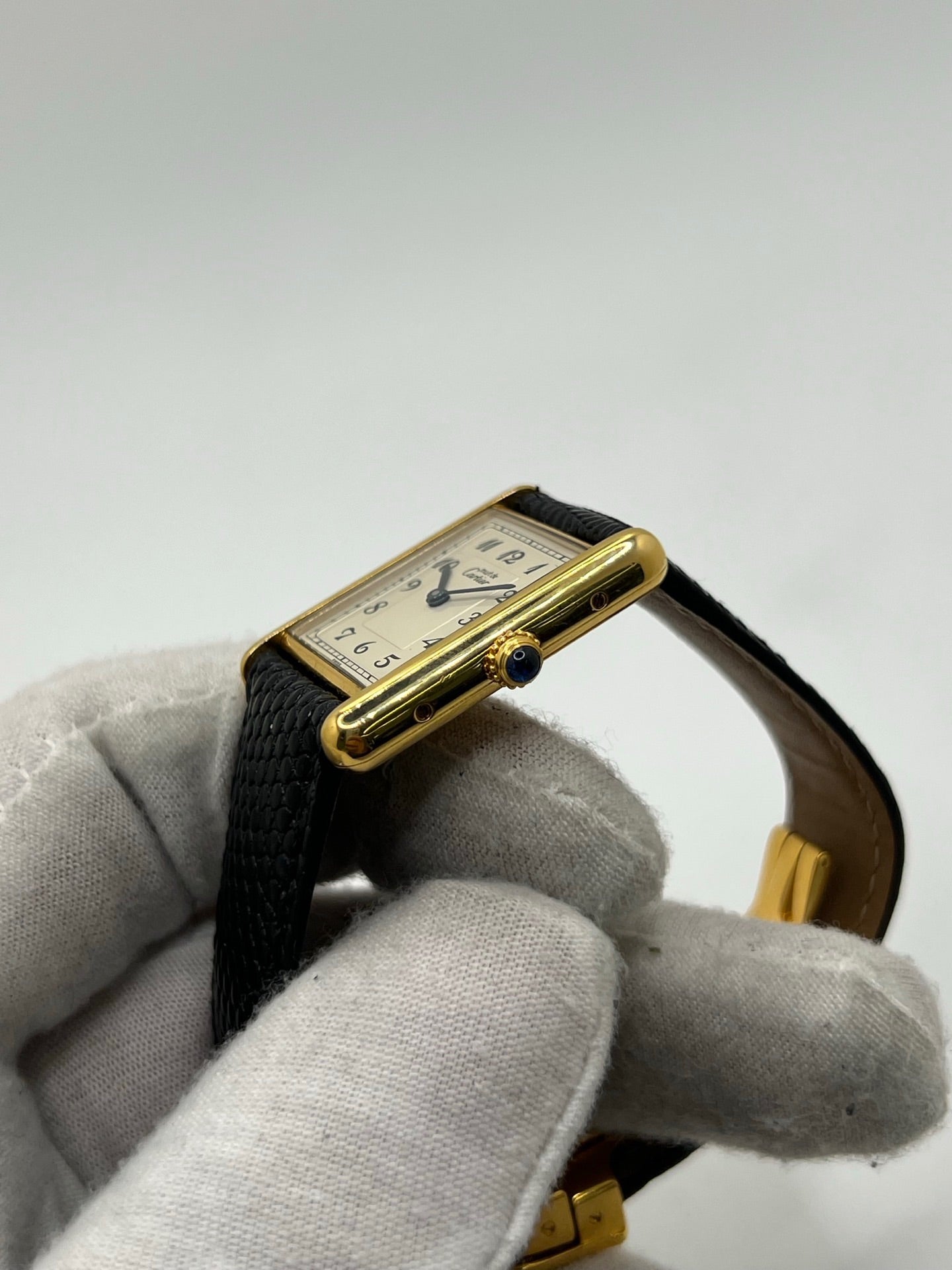 Montre Cartier Tank Vermeil référence 590005 vintage de 1989, avec boîtier rectangulaire en argent aux proportions classiques 23 x 30 mm, cadran argenté élégant avec chiffres arabes noirs et aiguilles bleuies, verre saphir et mouvement quartz. Montée sur un bracelet en cuir de lézard noir avec boucle ardillon en acier. Modèle iconique au design intemporel, livré avec son coffret et ses papiers d’origine, en très bon état.