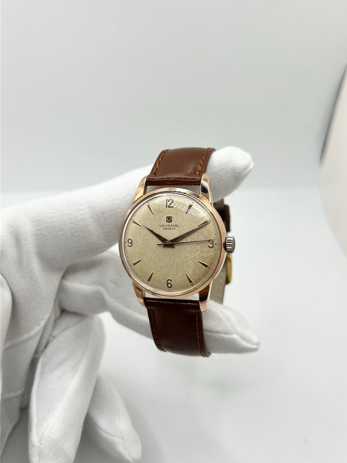 Montre Universal Genève 412501/1 vintage en très bon état, datant approximativement de 1950, avec un mouvement à remontage manuel. Son boîtier de 34,5 mm plaqué or est associé à un cadran blanc à chiffres arabes et un verre Plexiglas. Cette montre Universal Genève possède un bracelet en cuir brun avec boucle ardillon en acier. Un modèle homme ou unisexe au style classique et élégant, idéal pour les amateurs d’horlogerie vintage.