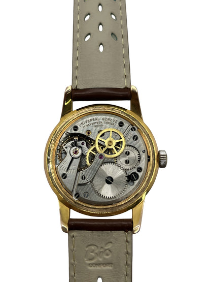 Montre Universal Genève 412501/1 vintage en très bon état, datant approximativement de 1950, avec un mouvement à remontage manuel. Son boîtier de 34,5 mm plaqué or est associé à un cadran blanc à chiffres arabes et un verre Plexiglas. Cette montre Universal Genève possède un bracelet en cuir brun avec boucle ardillon en acier. Un modèle homme ou unisexe au style classique et élégant, idéal pour les amateurs d’horlogerie vintage.