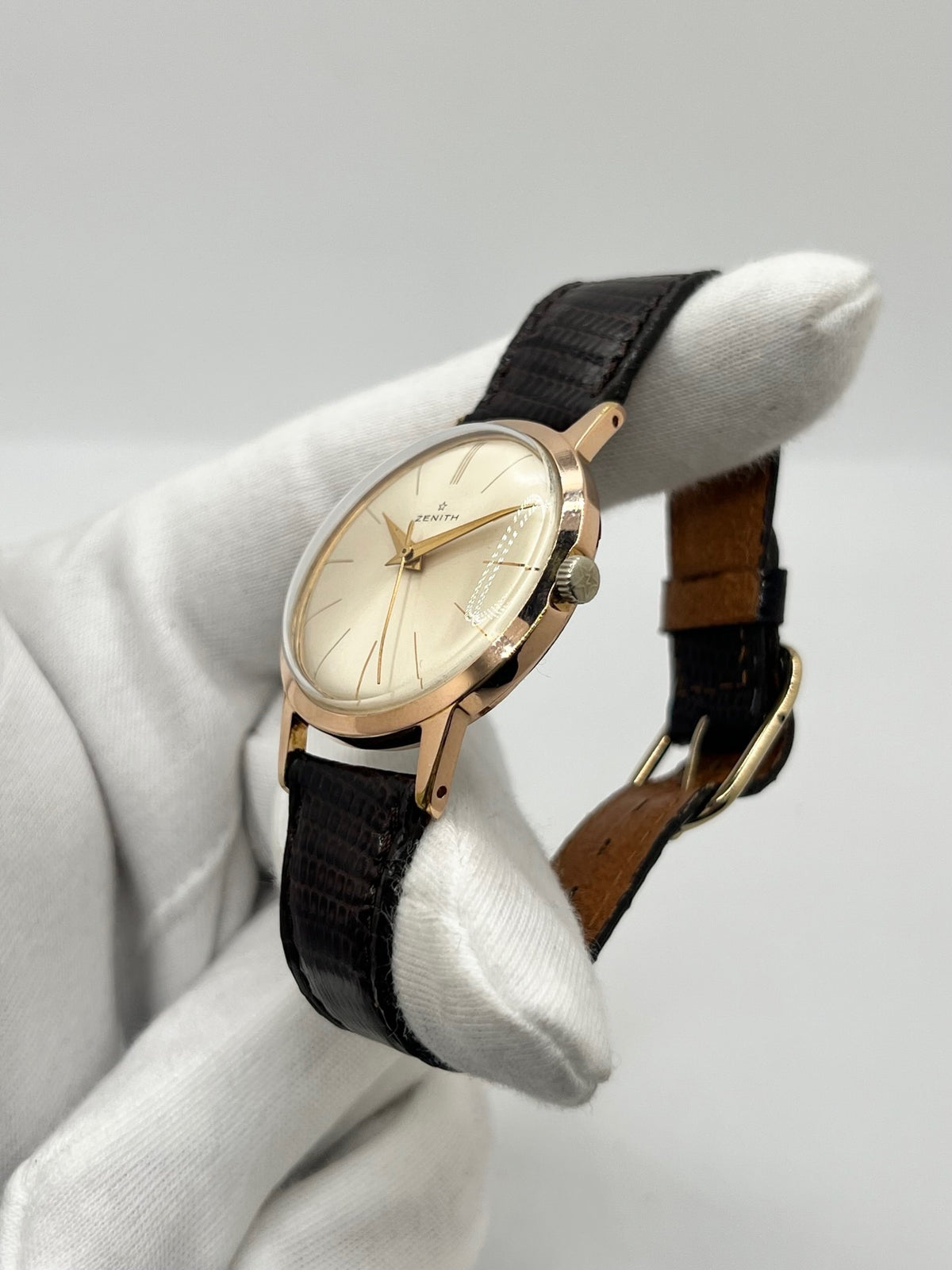 Montre Zenith Stellina vintage à remontage manuel, dotée d’un boîtier plaqué or et d’un élégant cadran champagne. Cette montre Zenith se distingue par son style classique et intemporel, emblématique de l’horlogerie traditionnelle. Elle est équipée d’un bracelet brun en cuir de lézard, complété par une boucle ardillon en acier. Avec son esthétique raffinée et son allure rétro, la Zenith Stellina séduit les amateurs de montres anciennes et de pièces horlogères au charme authentique.