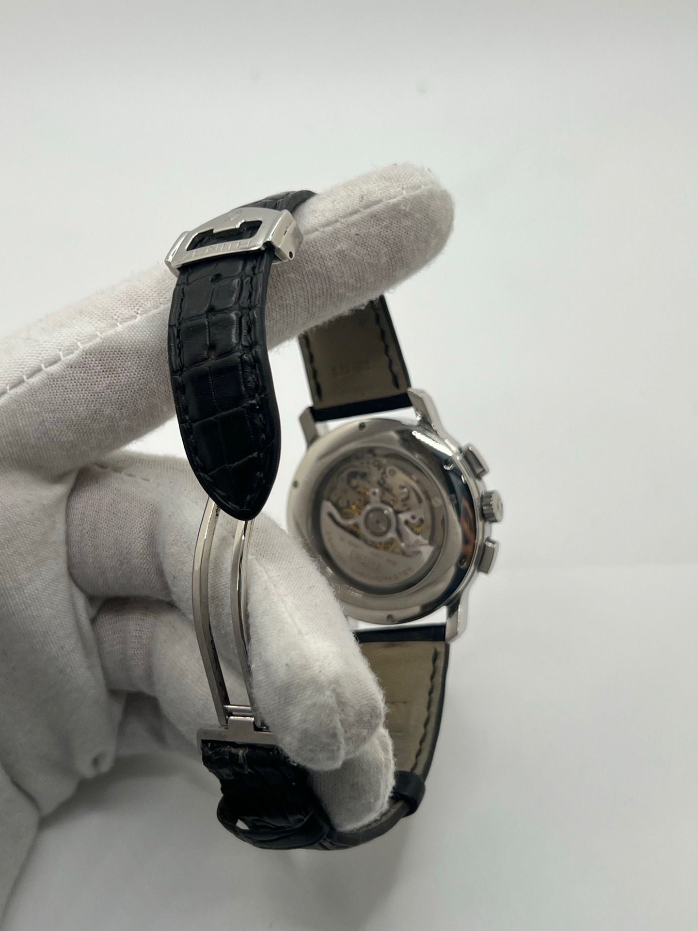 Montre chronographe automatique en acier avec cadran argenté à chiffres romains, fonction phase lunaire, date, jour et mois. Boîtier de 40 mm, verre saphir, fond transparent et bracelet en cuir noir. Modèle de haute précision doté du calibre 410 avec 50 heures de réserve de marche. Montre élégante pour homme ou unisexe.