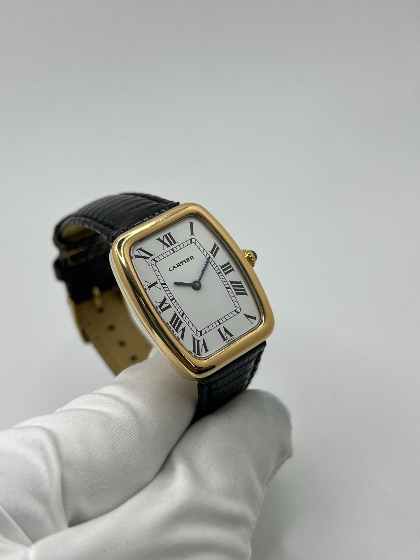 Montre Cartier Fabergé vintage en or jaune avec boîtier rectangulaire de 26 mm, cadran blanc à chiffres romains et bracelet en cuir noir. Ce modèle élégant à remontage manuel, fabriqué vers 1970, séduit par son style intemporel et raffiné. Montre homme ou unisexe d’occasion en très bon état, livrée avec coffret d’origine, idéale pour les amateurs d’horlogerie de luxe et de pièces vintage authentiques.
